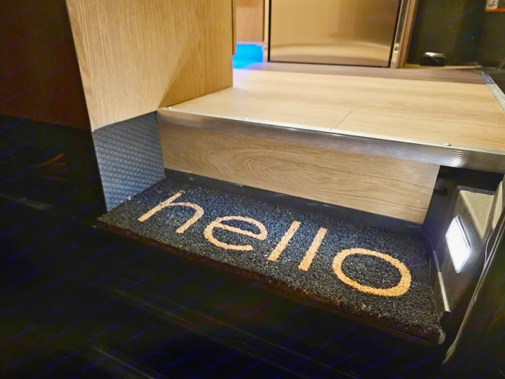Welcome aboard your RV rental! A "hello" doormat greets you at the illuminated entrance step, leading to the cozy interior.. Mercedes-Benz Sprinter 2023