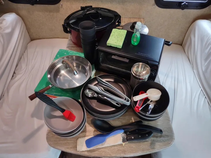 RV rental kitchen setup: slow cooker, toaster oven, plates, pots, and utensils neatly arranged for camping convenience.. Thor Windsport 2015
