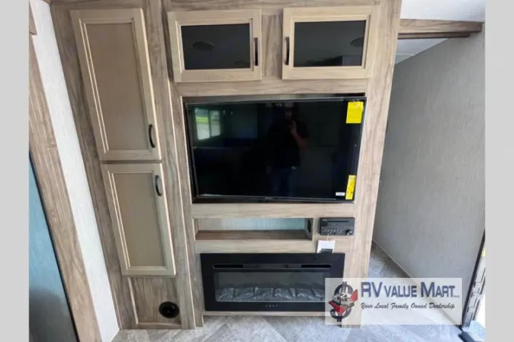 RV rental interior featuring a modern entertainment center with a large TV, electric fireplace, and built-in cabinets.. Forest River Palomino Solaire 2023