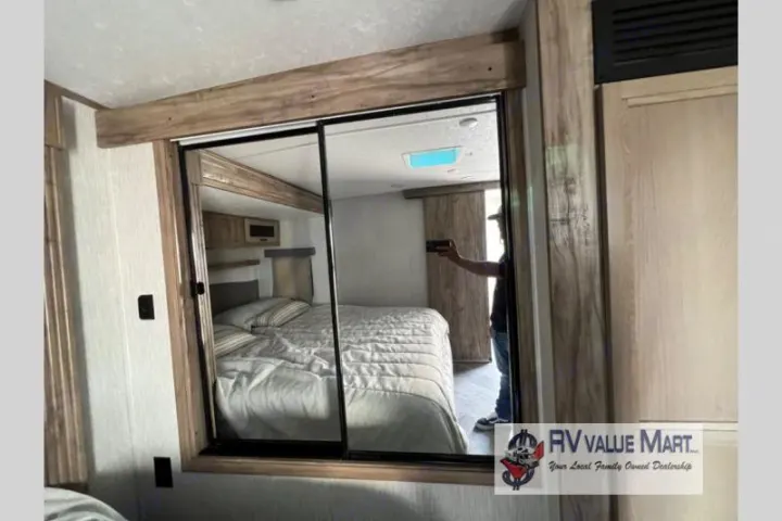 RV rental bedroom featuring a large mirrored closet, reflecting the comfortable bed and overall interior space.. Forest River Palomino Solaire 2023