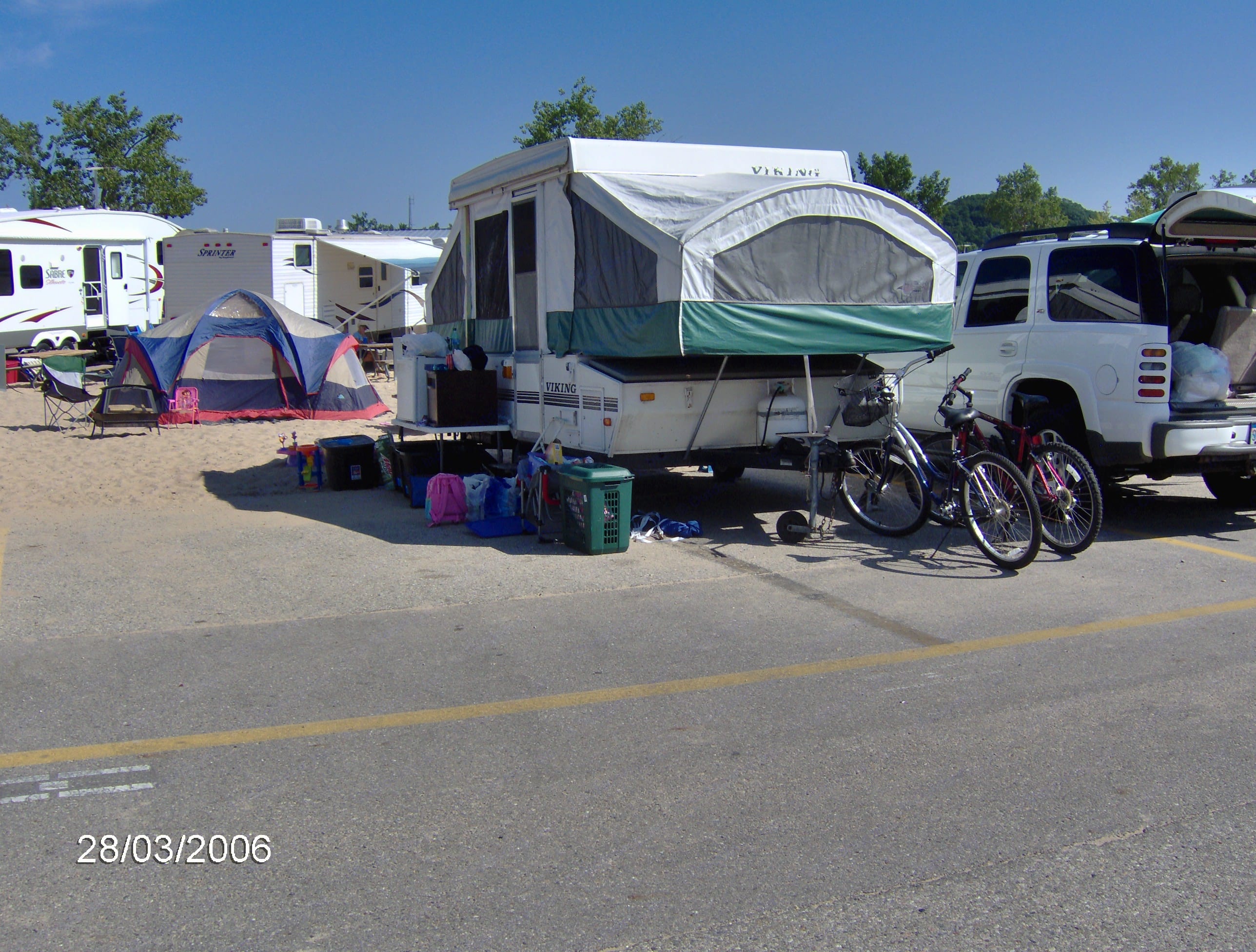 Sunny campsite with a pop-up RV rental, tent, and bicycles, ready for family outdoor adventures.. Viking 1906 2001
