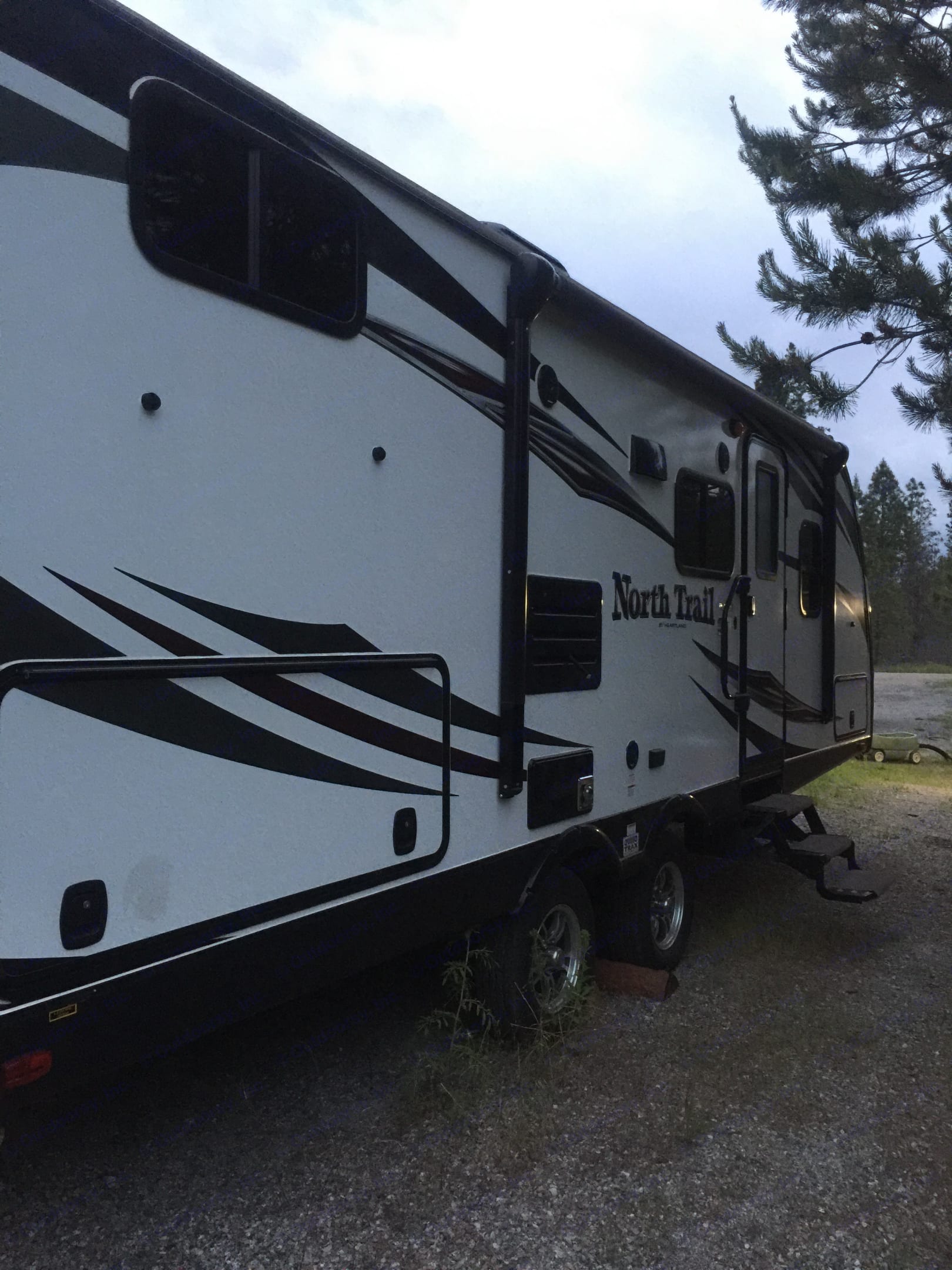North Trail RV rental, a white travel trailer with black graphics, parked on a gravel lot under trees, ready for your trip.. Other North Trail 2017