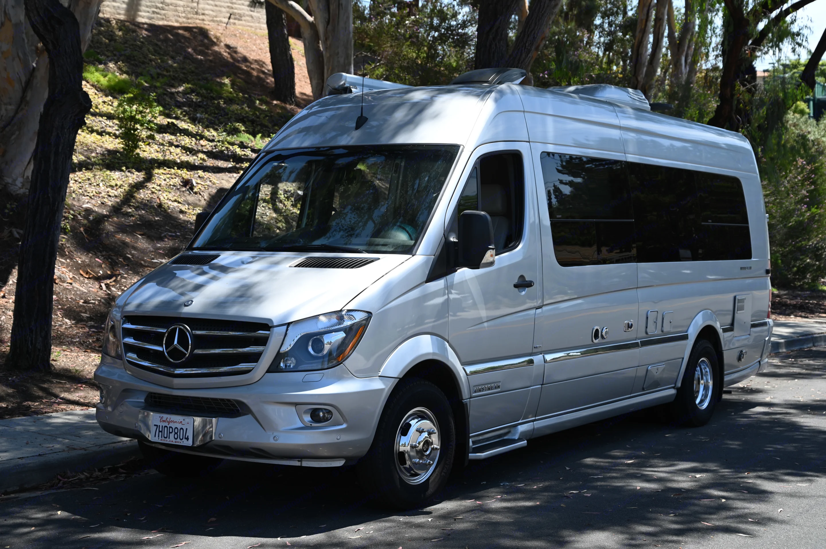 A silver Mercedes-Benz Sprinter RV, an Airstream camper van, is available for rv rental, parked on a sunlit street.. Airstream Airstream 2014