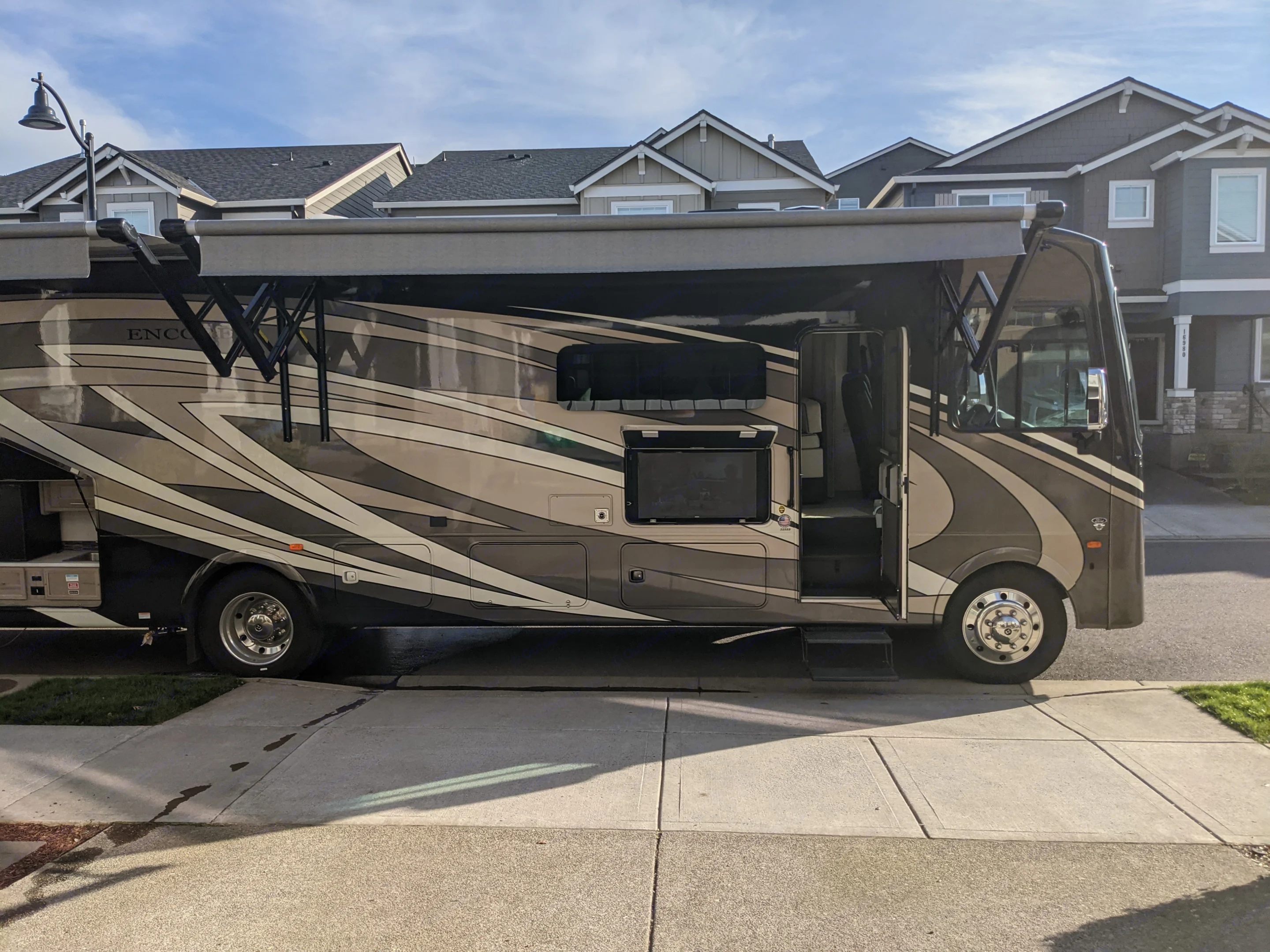 Camping Side of RV with Kitchen and TV Bay Open and Awnings Extended. Forest River Coachmen Encore 2021