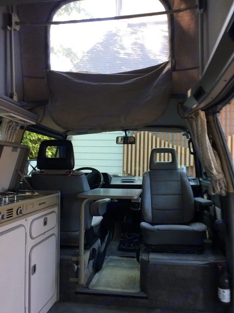 RV rental interior: View into a classic VW Westfalia camper van with pop-top, kitchen, and swivel seats.. Volkswagen T3 Westfalia 1988