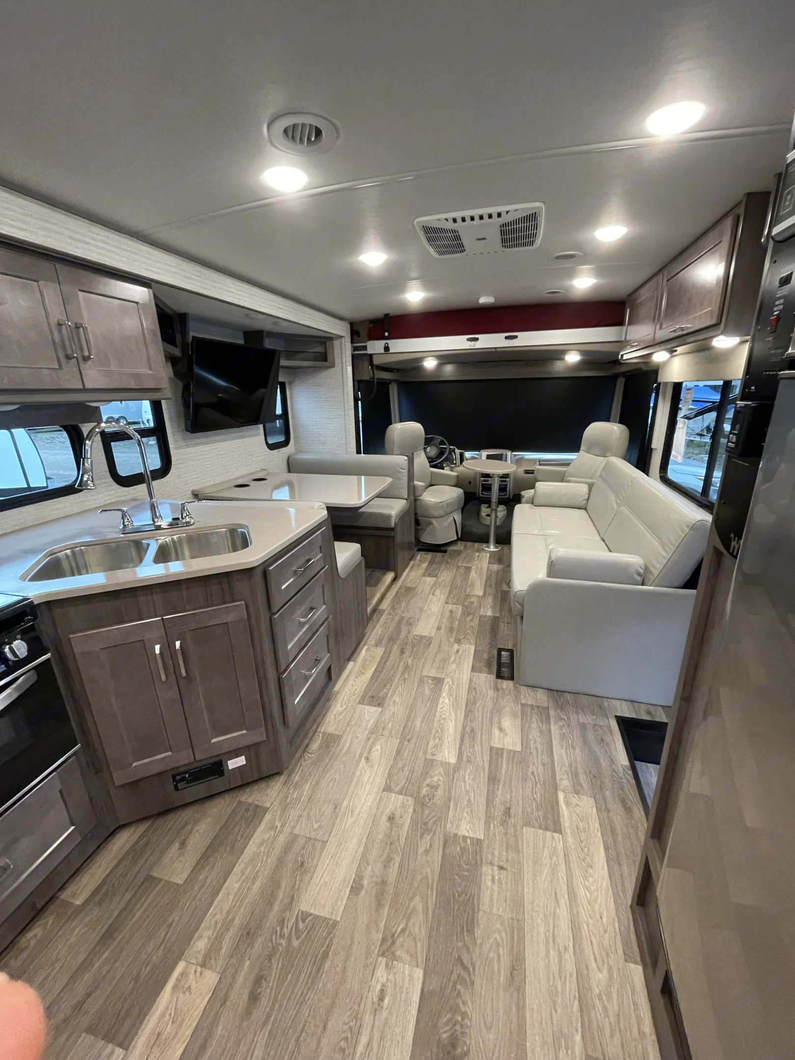 Spacious RV rental interior featuring a modern kitchen, comfortable dinette, sofa, and cockpit area with wood-look flooring.. Winnebago Vista 2022