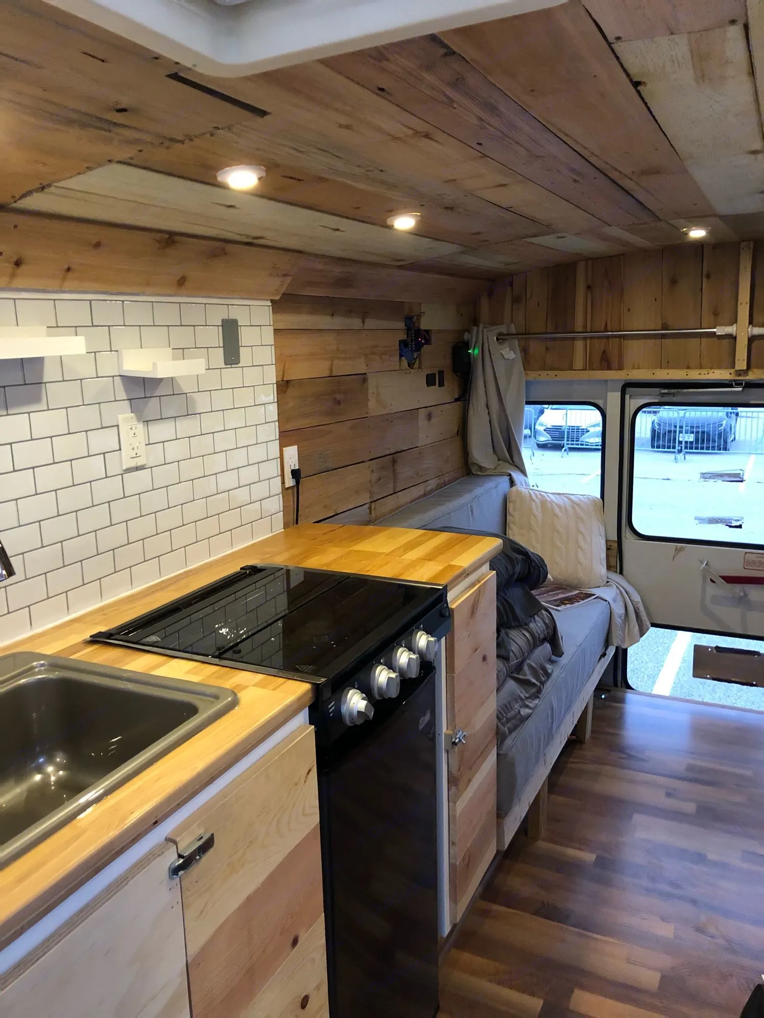 RV rental: Cozy wood-paneled van conversion interior with kitchen, bed, subway tile backsplash, and warm lighting.. Chevy Express 3500 Mini Bus 2002