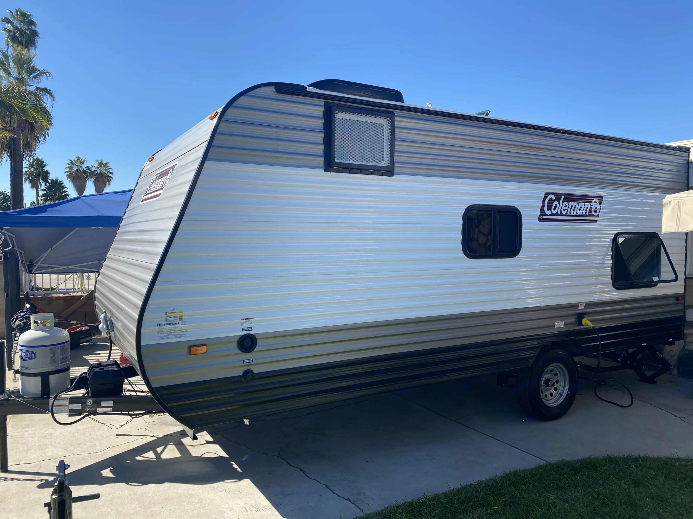 A sleek Coleman travel trailer, perfect for RV rental getaways. Parked on concrete under a clear sky.. Coleman Lantern 17 B 2022