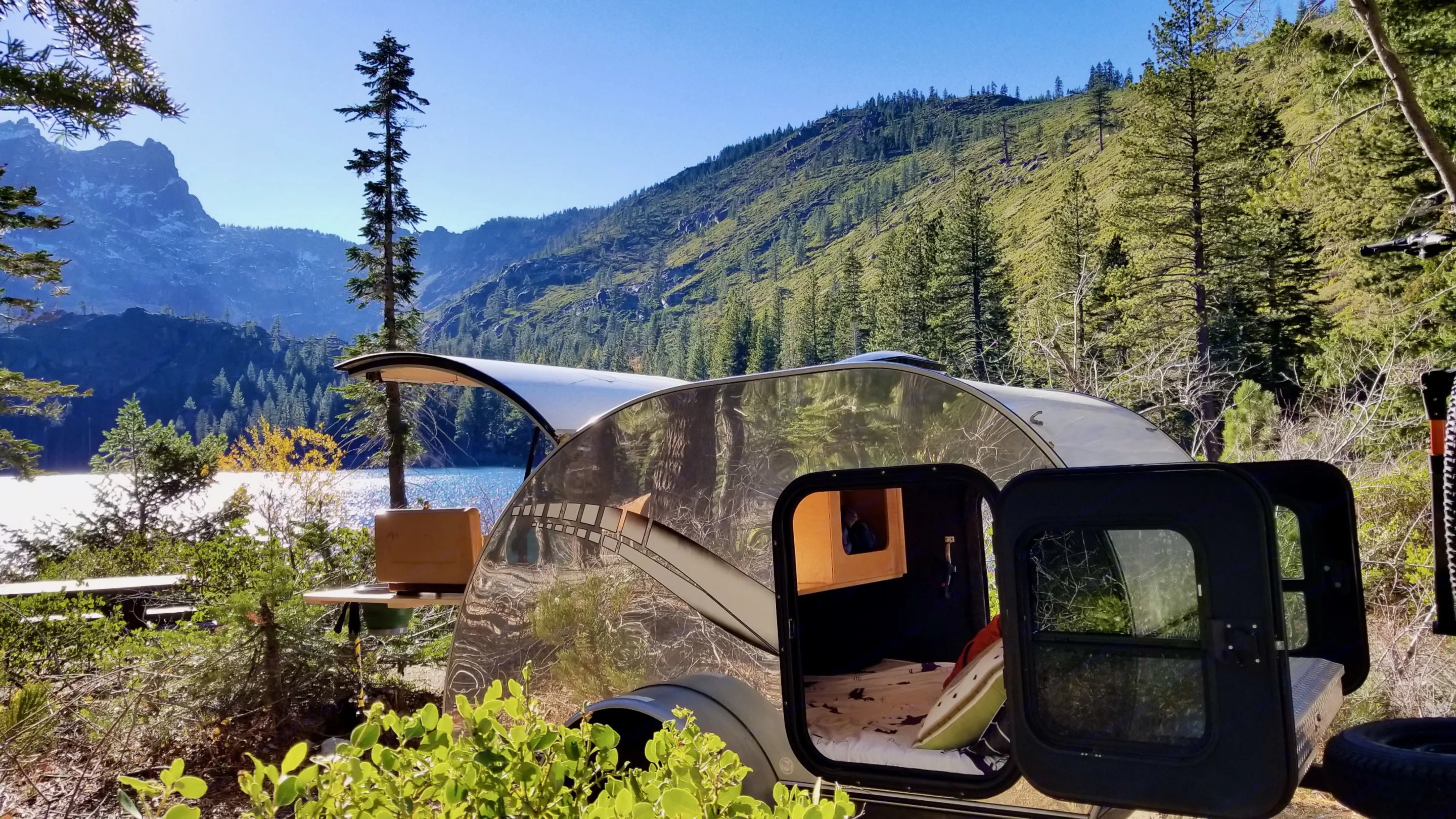Experience nature: This RV rental, a shiny teardrop trailer, opens to a cozy interior and kitchenette, set by a scenic lake and mountains.. Other Other 2011