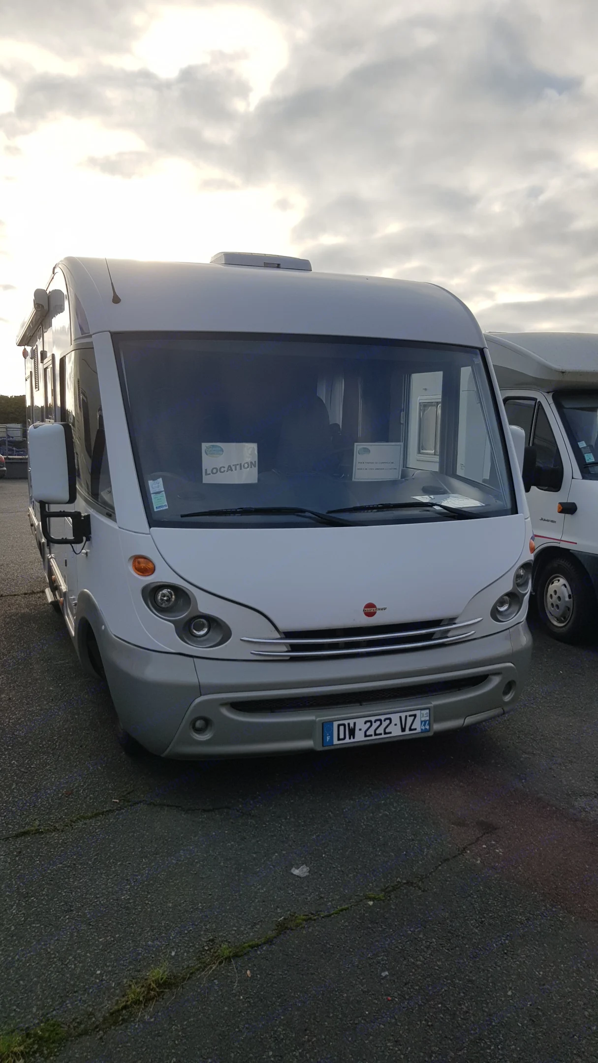 White and grey motorhome, identified as an **RV rental**, parked on asphalt under a cloudy sky. "LOCATION" sign visible inside.. BURSTNER Elegance i 685 2006