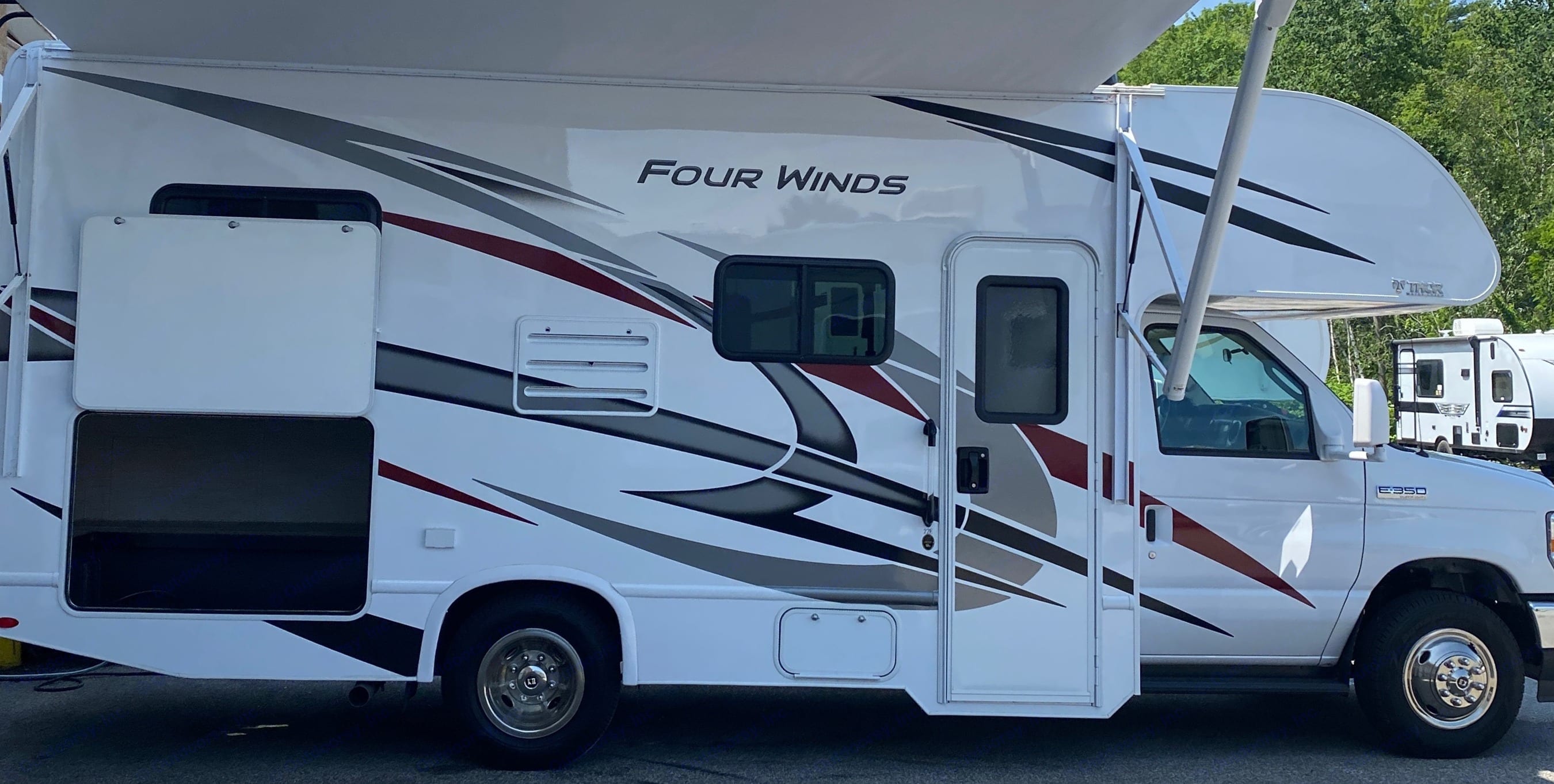 Passenger side showing rear cargo hold and awning open. Thor Four Winds 2021