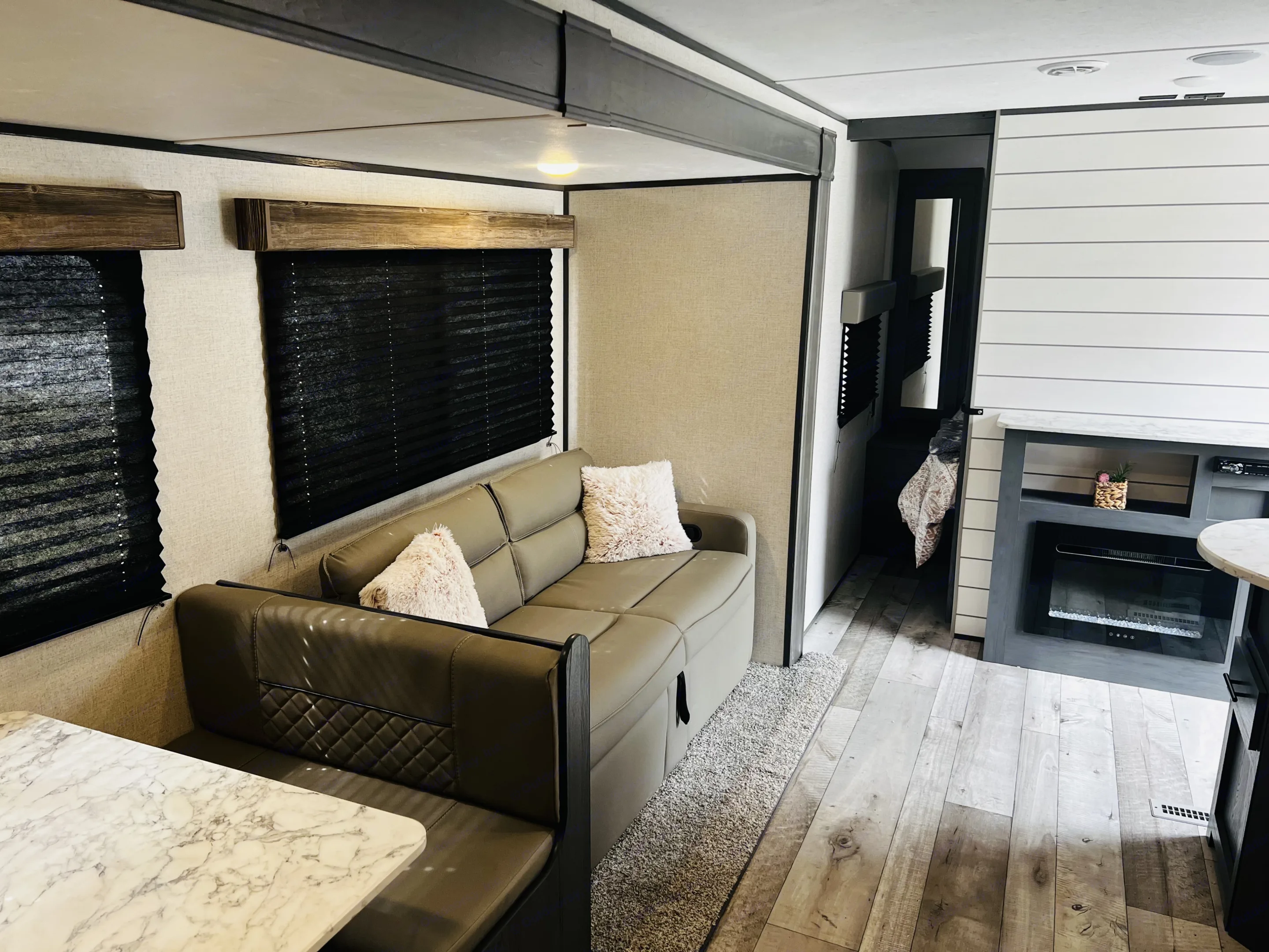 RV rental living space with a modern sectional sofa, marble-look dinette, and electric fireplace.. Dutchmen Aspen Trail LE 2023