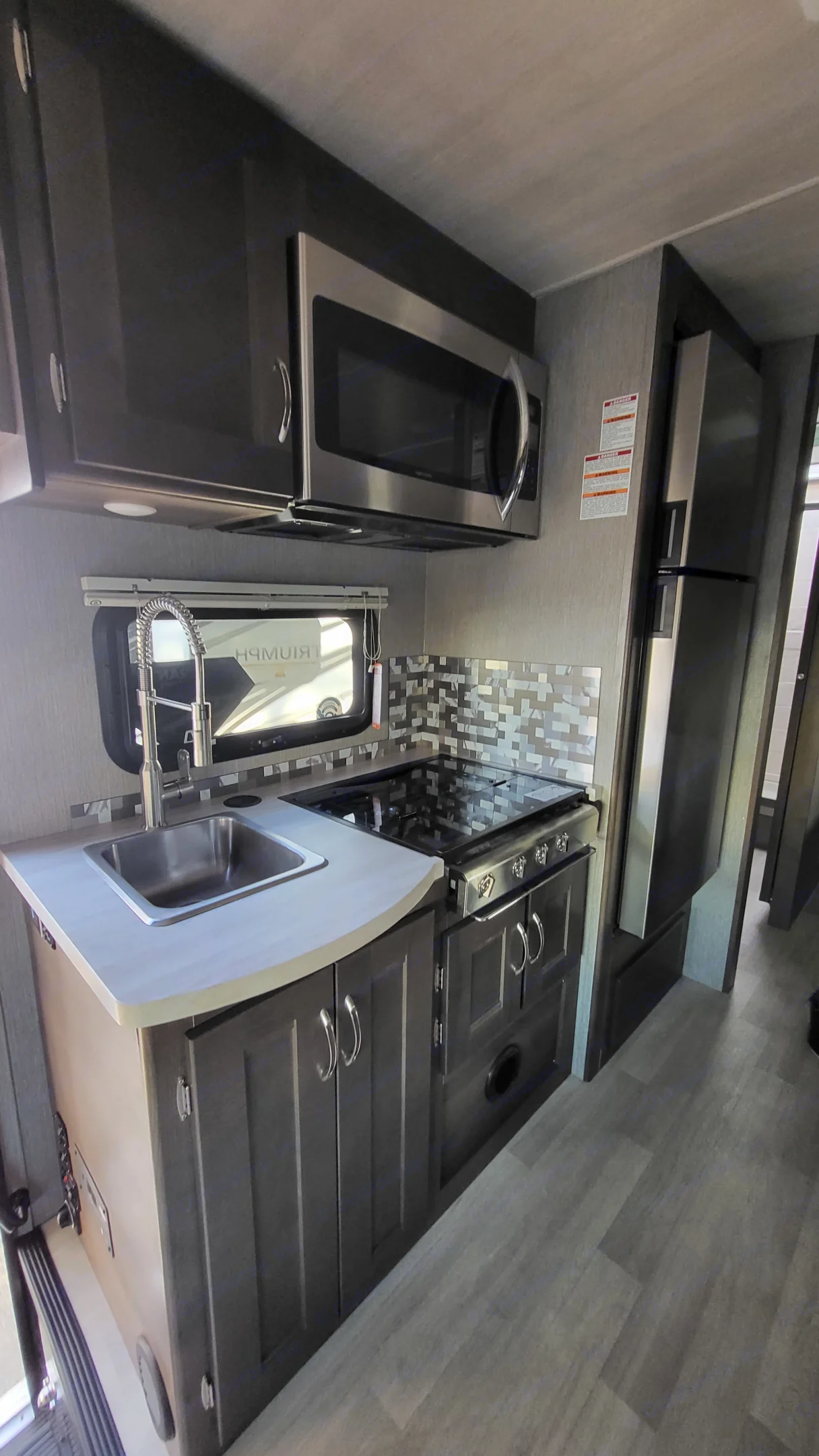 3 burner gas cooktop with backsplash, full size house kitchen faucet, full size house microwave, full size fridge.. Nexus RV Triumph 2022