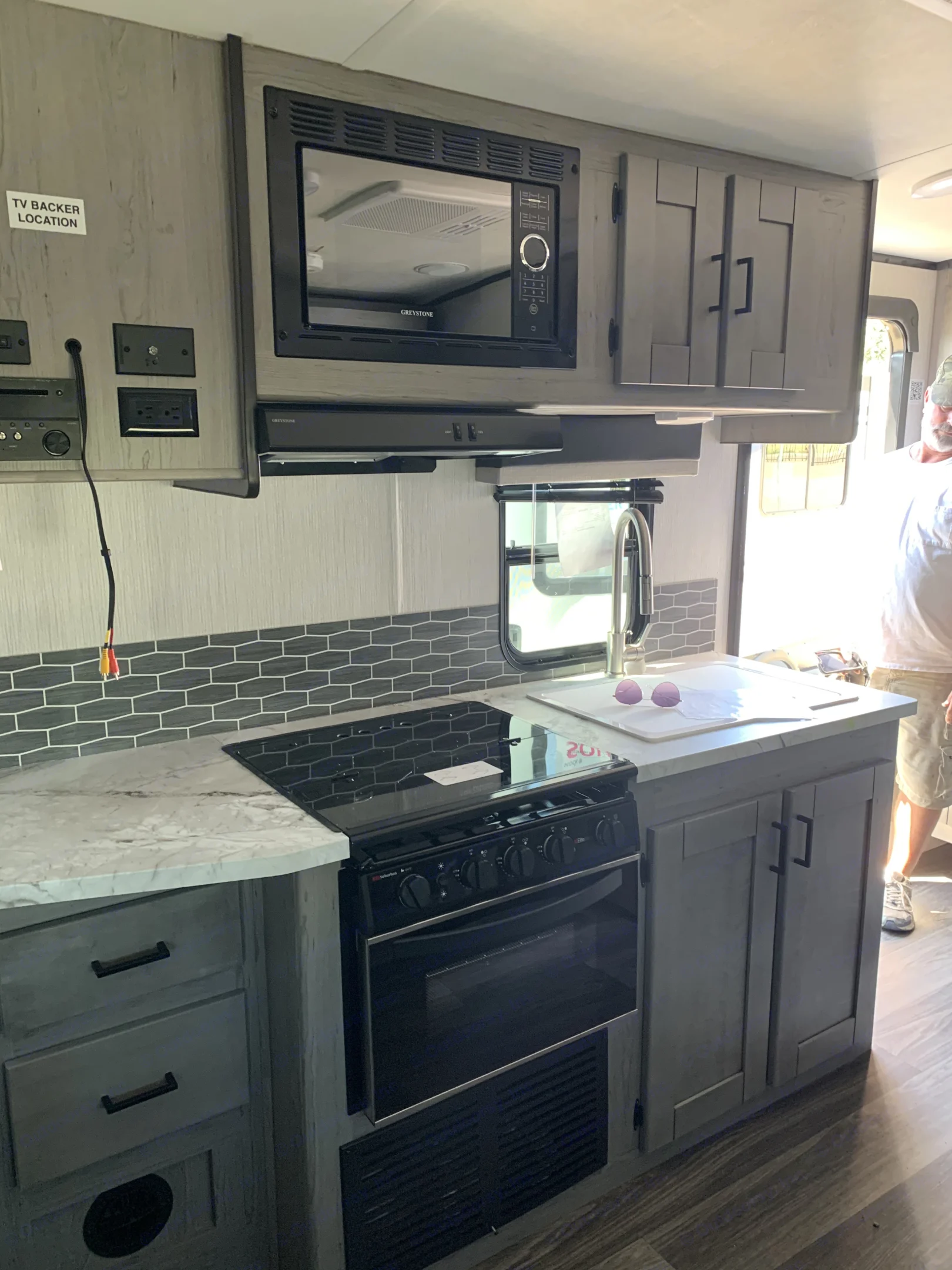 Inside an rv rental: a well-equipped kitchen with a Greystone microwave, Suburban stove, sink, and sleek cabinetry.. Heartland RVs Mallard 2021