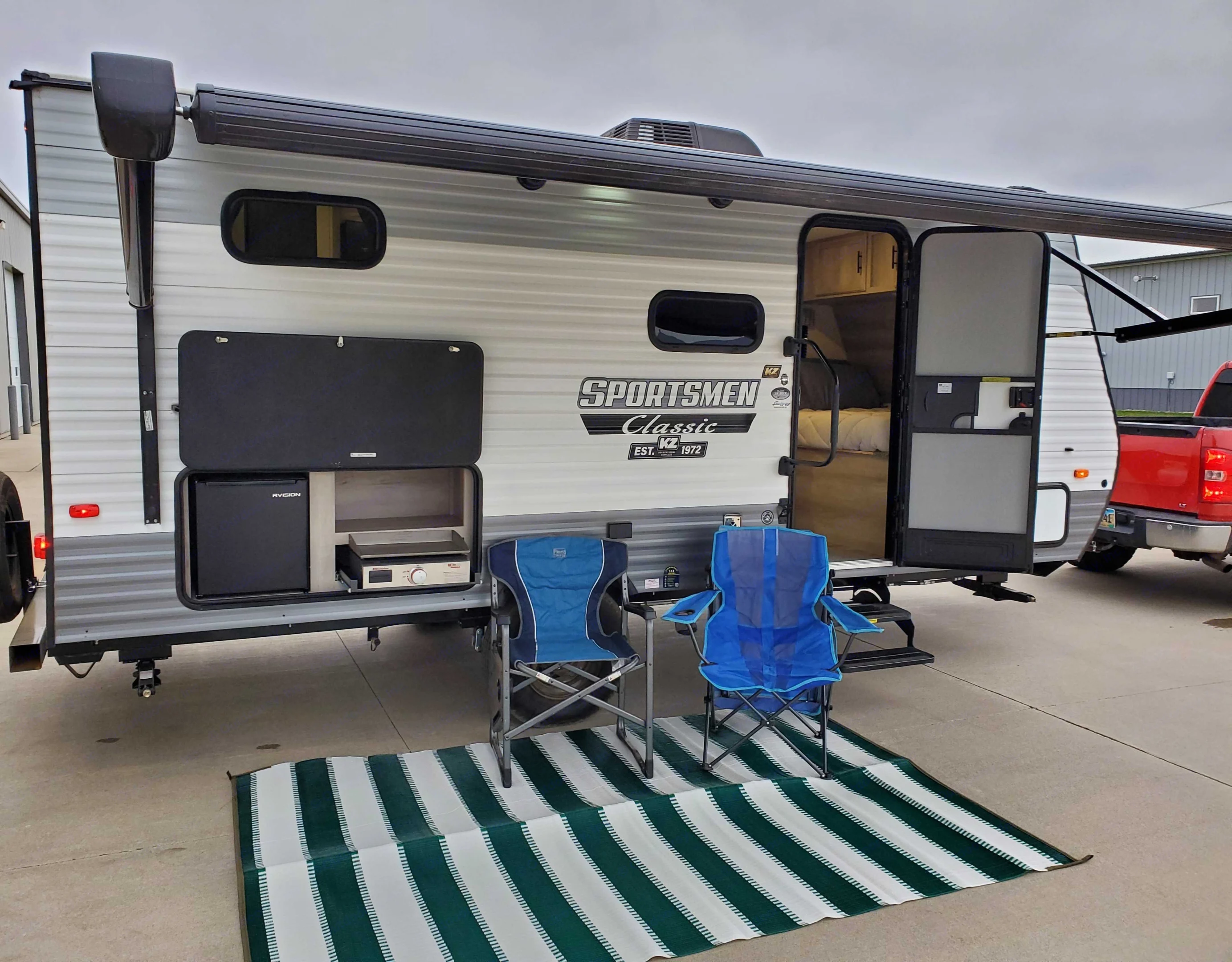 Front of camper. outdoor rug, and outdoor kitchen featured. KZ Sportsman 2022