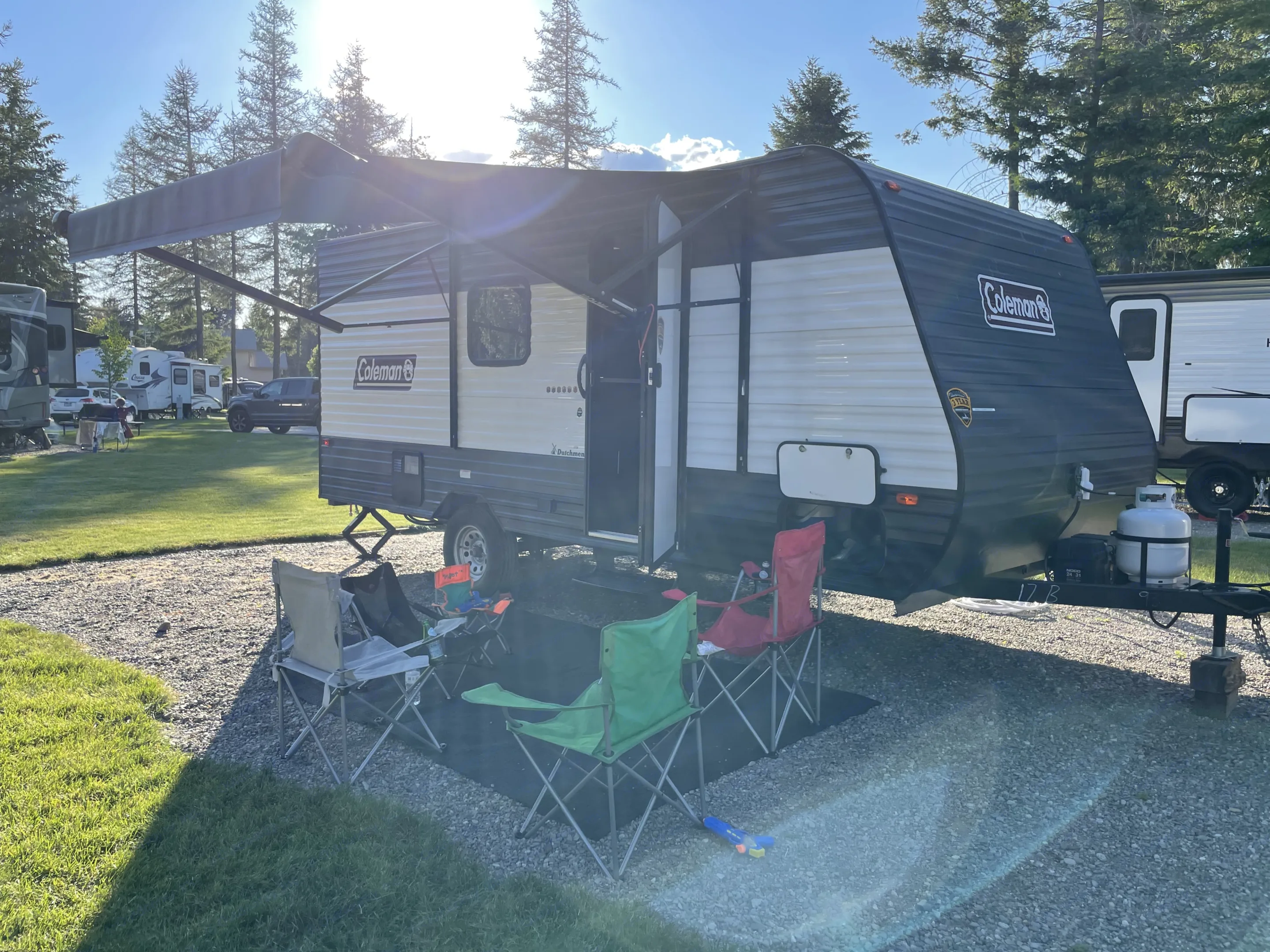 Enjoying outdoor leisure with a spacious rv rental travel trailer, set up with an awning & chairs at a sunny campground.. Dutchmen Coleman Lantern LT 2021