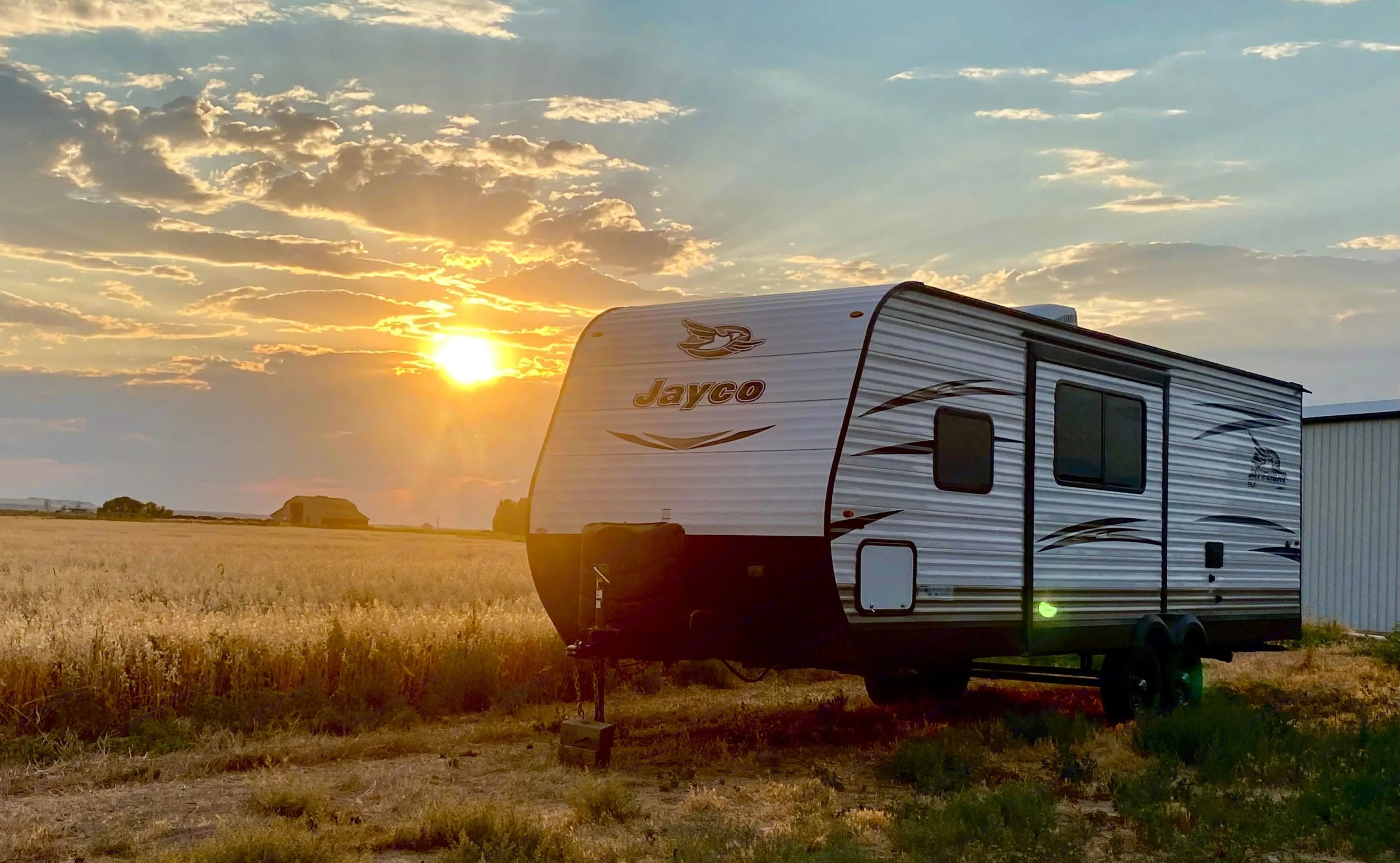 Golden sunset over a Jayco RV parked in a field. Ideal for an RV rental road trip or serene camp.. Jayco Jay Flight SLX 2018