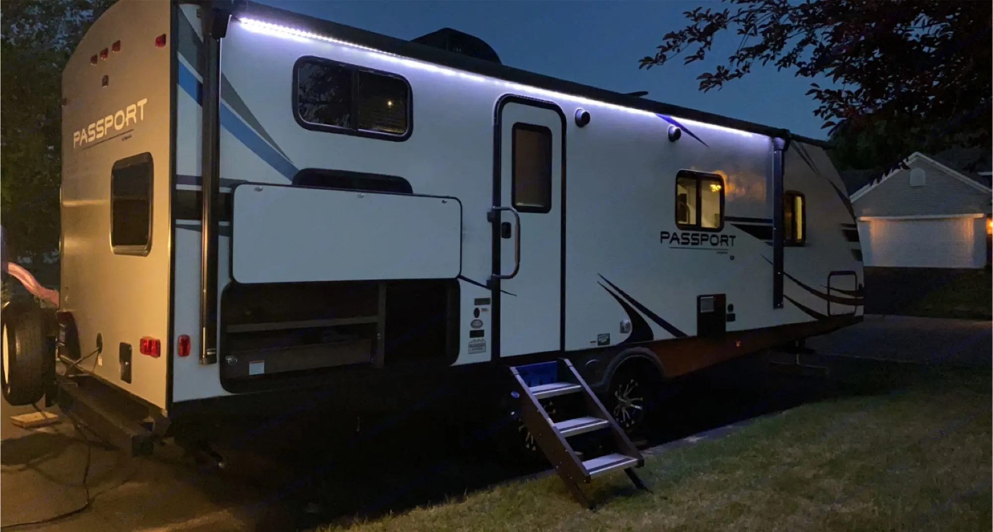 This Passport travel trailer, brightly lit at night, showcases an ideal RV rental setup with accessible steps.. Keystone Passport 2020