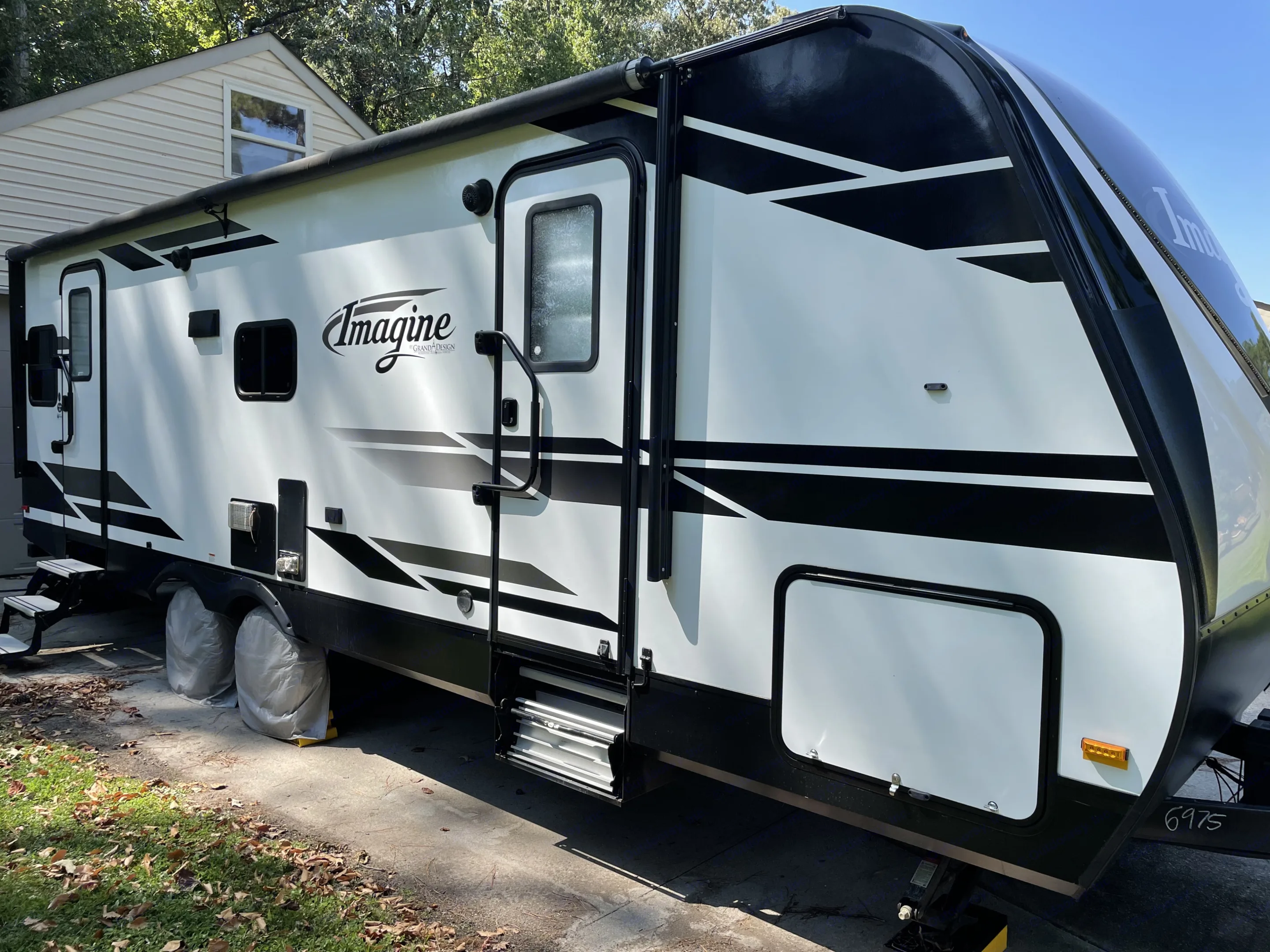 White & black Grand Design Imagine RV rental, parked with steps down, ready for your next adventure.. Grand Design Imagine 2019