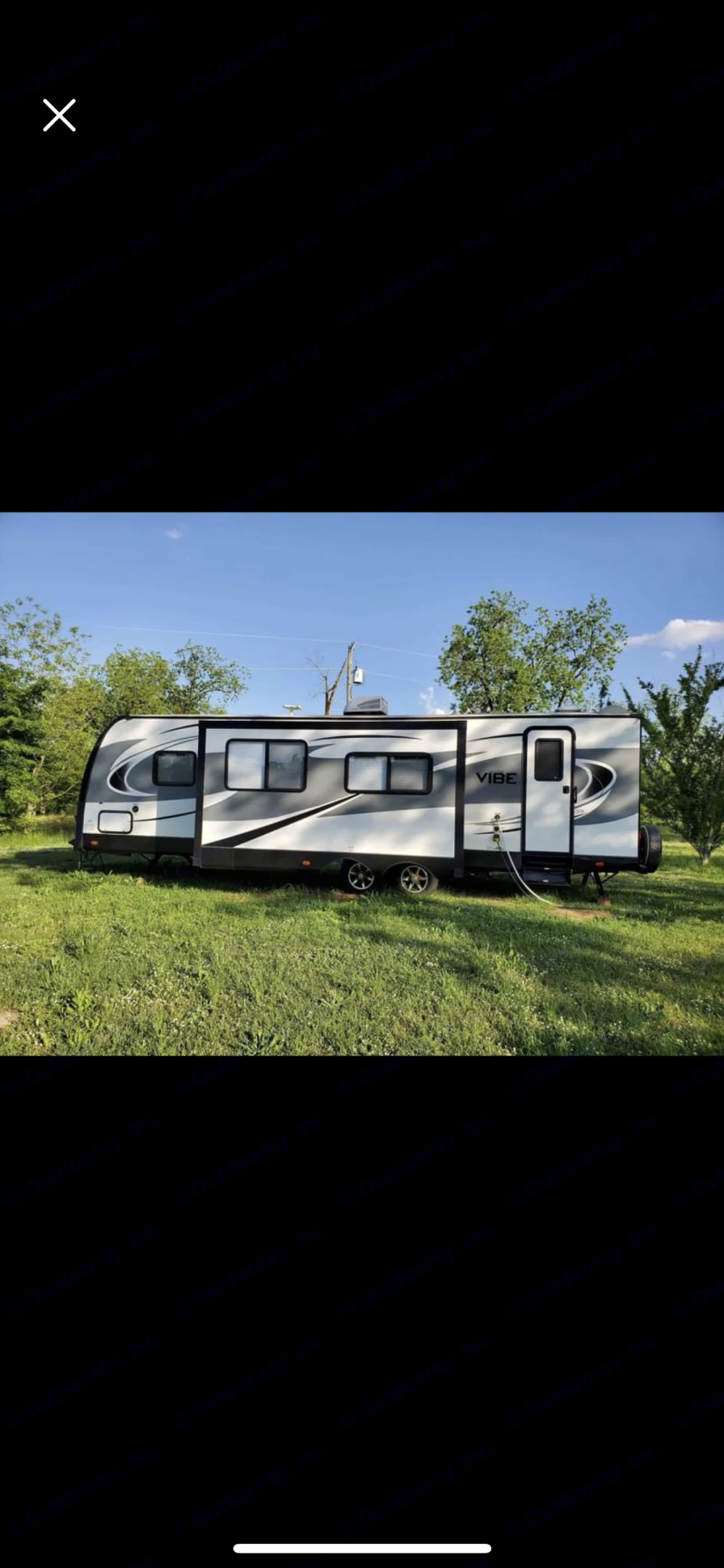 This Vibe RV rental, a white and gray travel trailer, is parked on green grass under a clear sky for outdoor adventures.. Forest River Vibe 2017