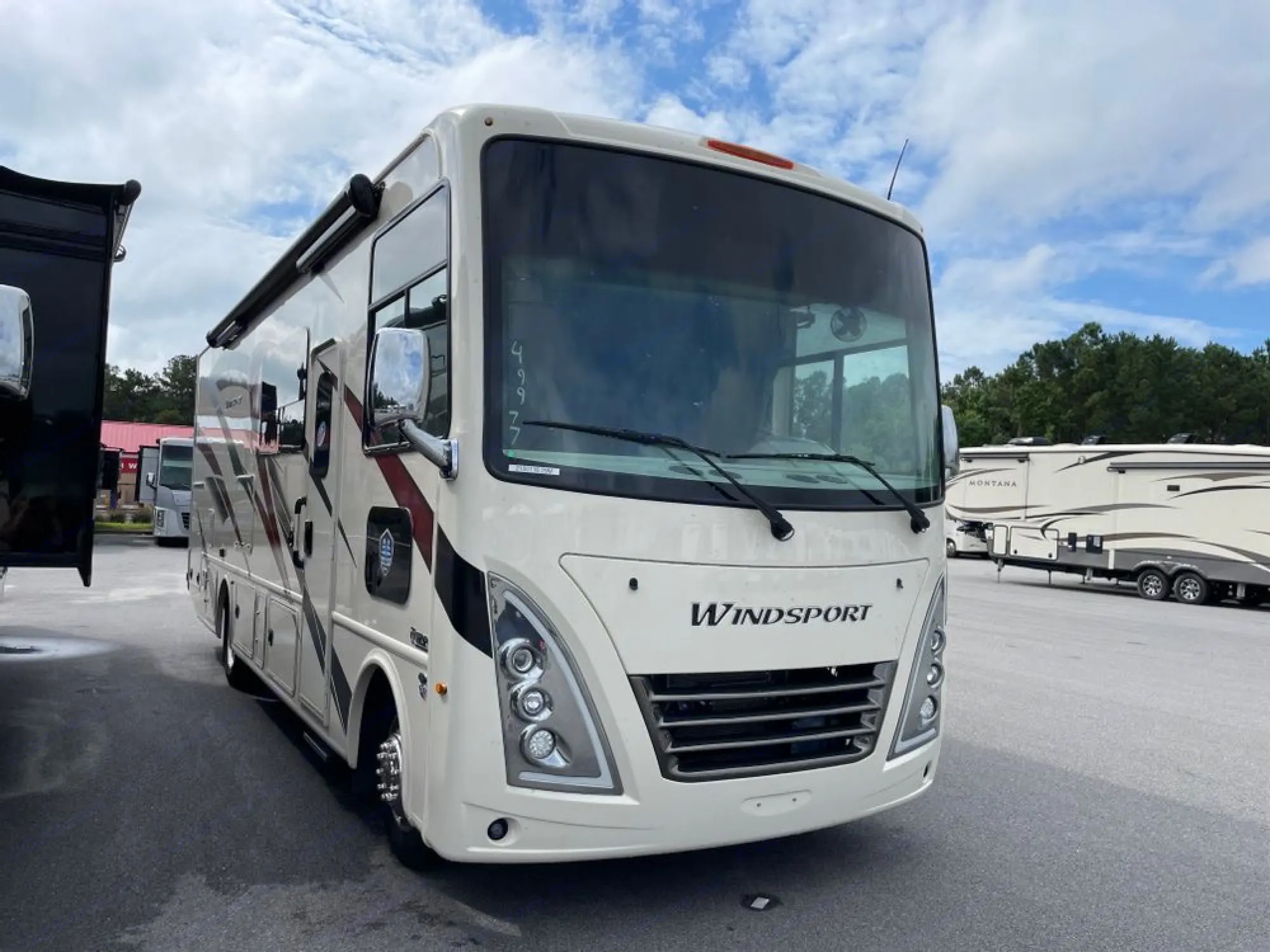 Cream Class A Windsport RV for rv rental, parked on an asphalt lot with other RVs under a cloudy sky.. Ford Windsport 2023