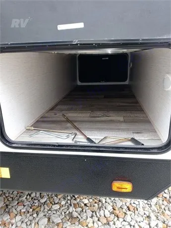 RV rental pass-through storage shown open, revealing a deep compartment with wood-look floor and tools.. Heartland RVs Sundance Ultra Lite 2022