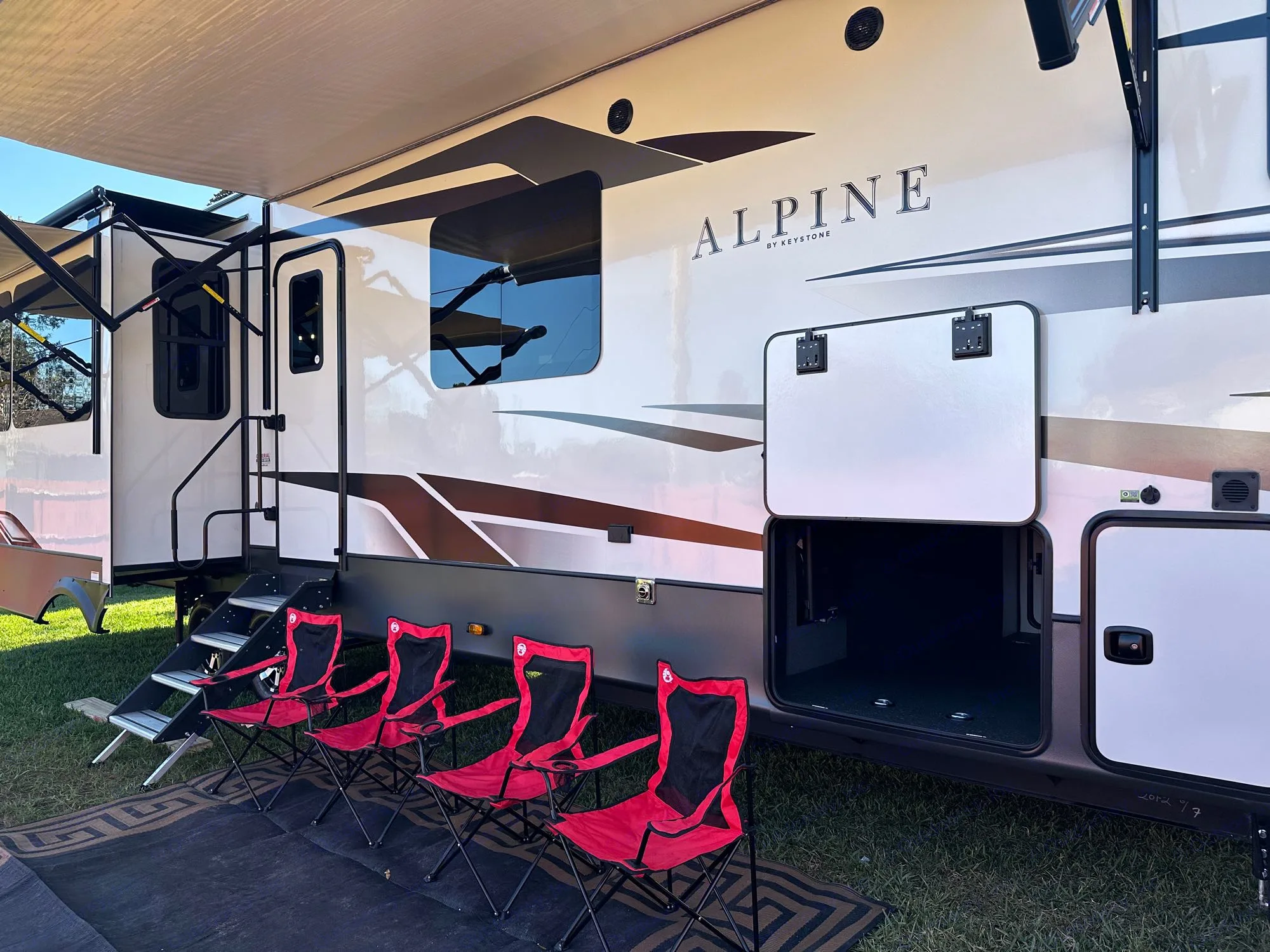 Spacious RV rental setup with extended awning, camping chairs, and ample storage for your travels.. Keystone RV Alpine 2022