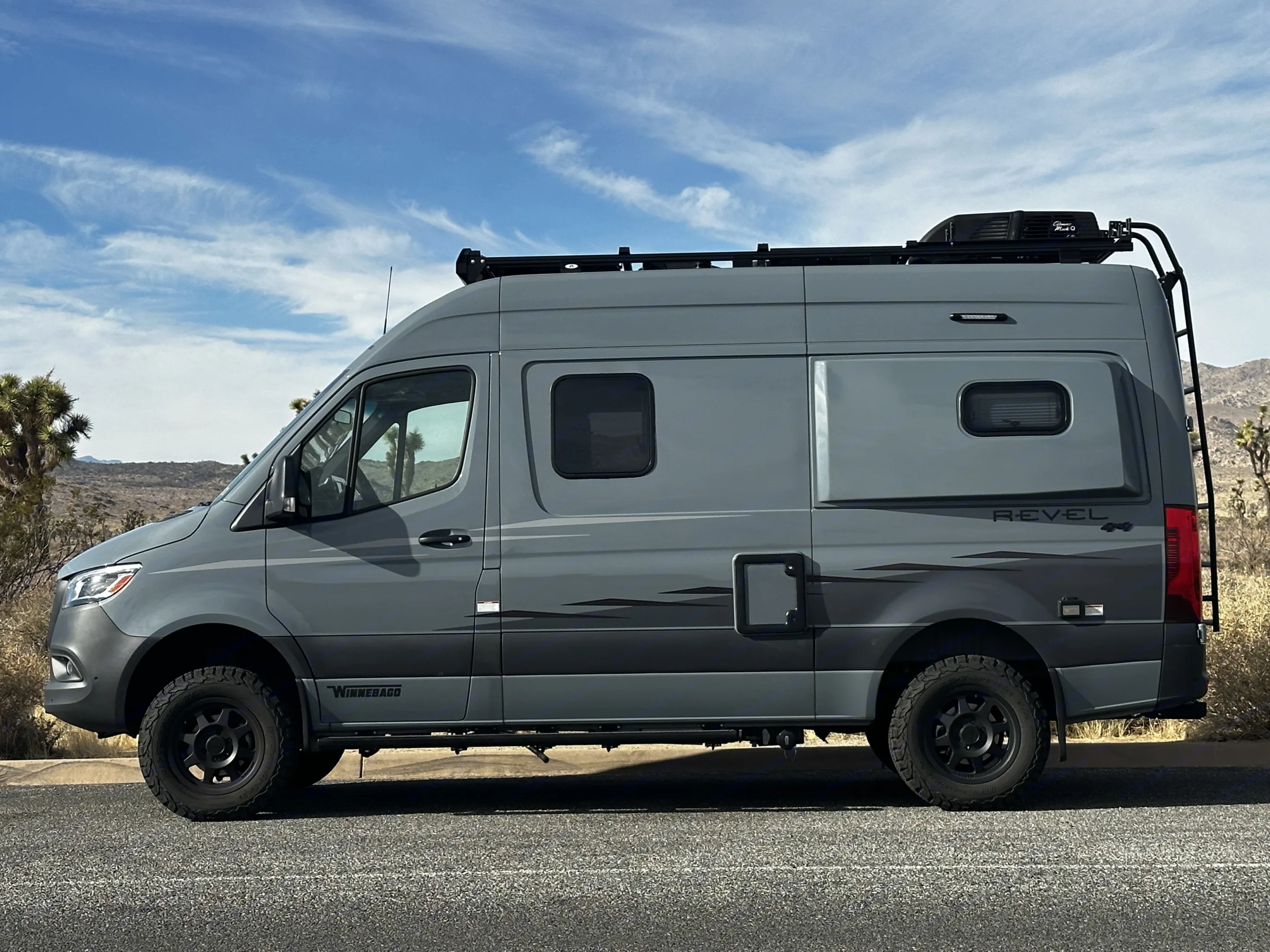 A gray Winnebago Revel 4x4 camper van with off-road tires,. Winnebago Revel 2023