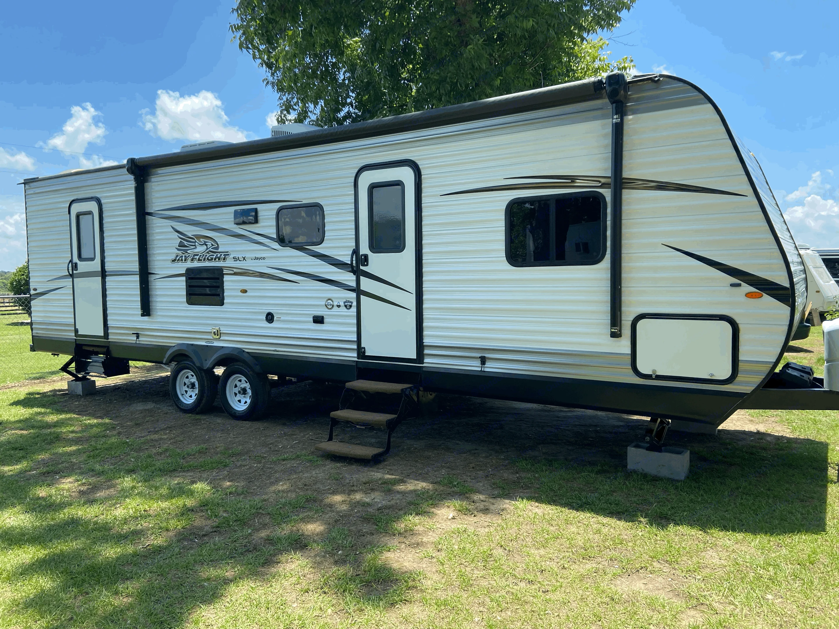 This Jayco travel trailer is available for rv rental! A spacious white and grey RV parked on sunny grass.. Jayco Jay Feather 2019