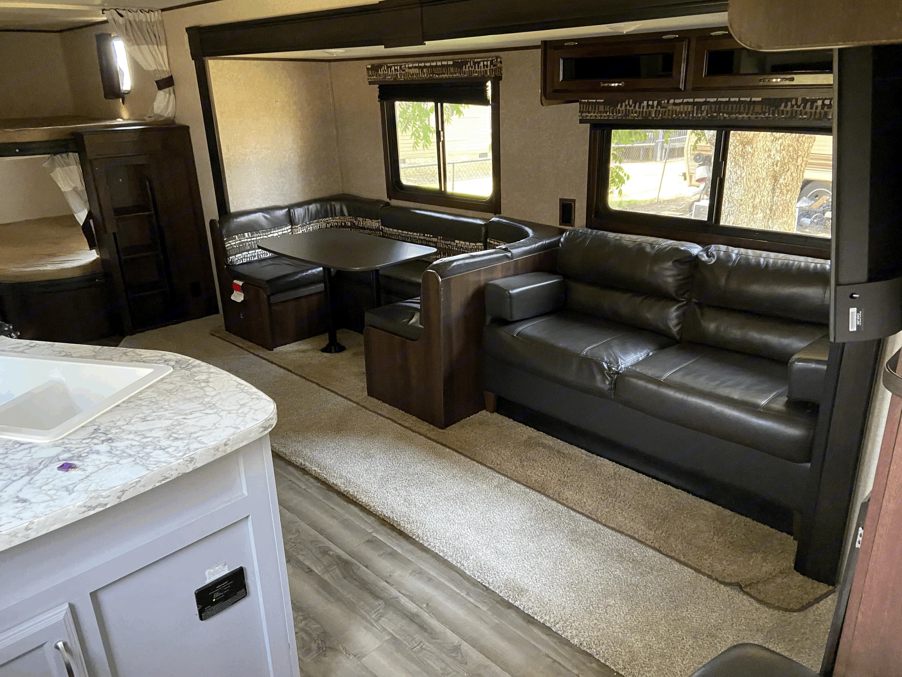 Spacious RV rental interior featuring a living area with a leather sofa, dinette, and bunk beds.. Jayco Jay Feather 2019