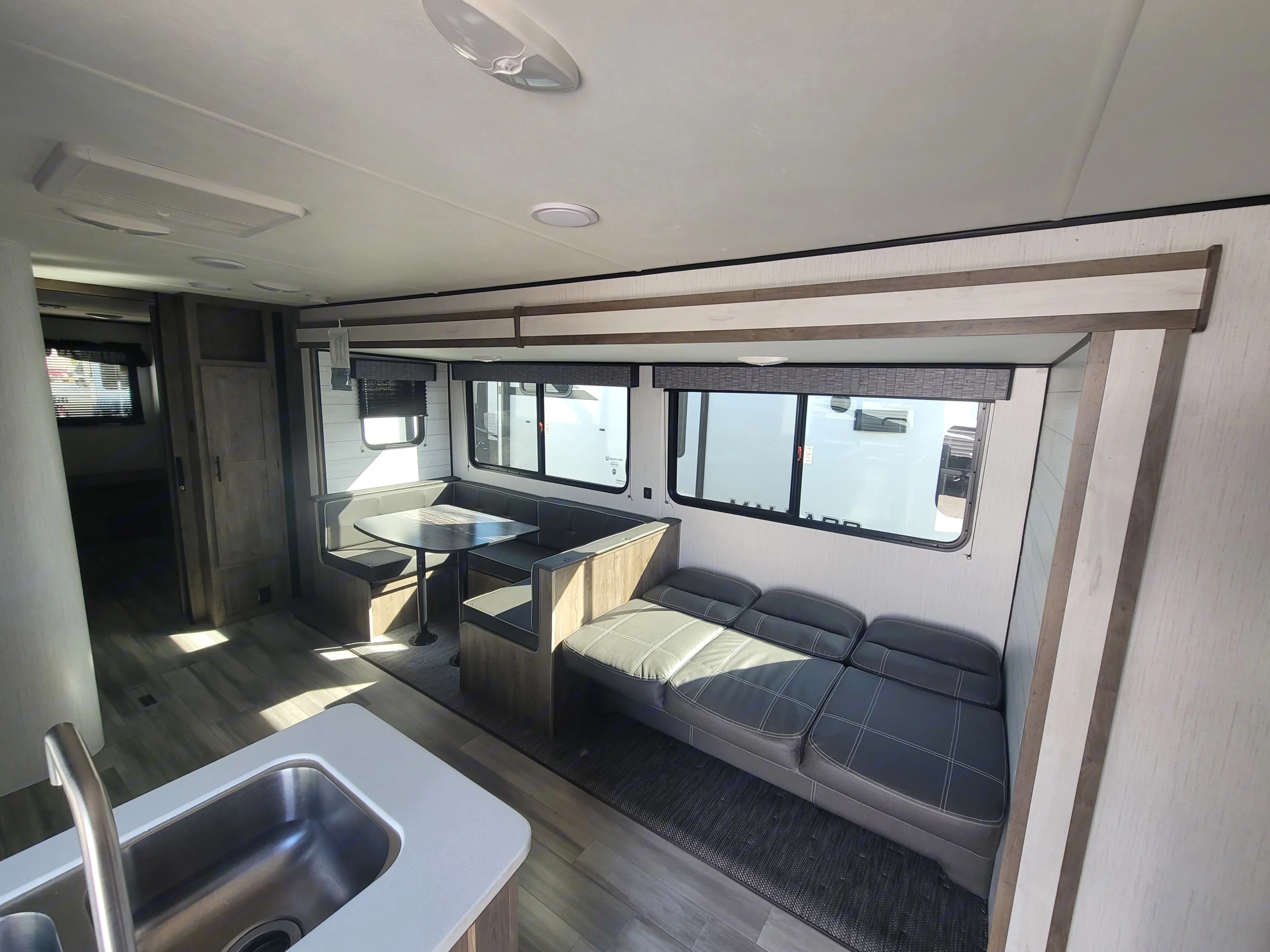 Spacious RV rental interior with a modern dinette, comfy sofa, and kitchen sink, perfect for your next adventure.. Heartland RVs Pioneer 2022