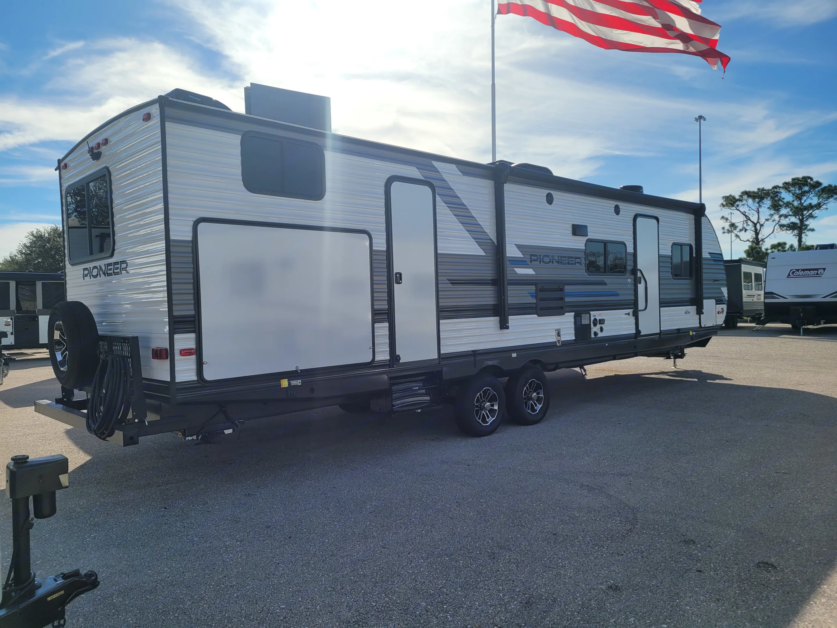 Explore this new Pioneer travel trailer, ideal for an RV rental adventure. Parked outside with a spare tire.. Heartland RVs Pioneer 2022