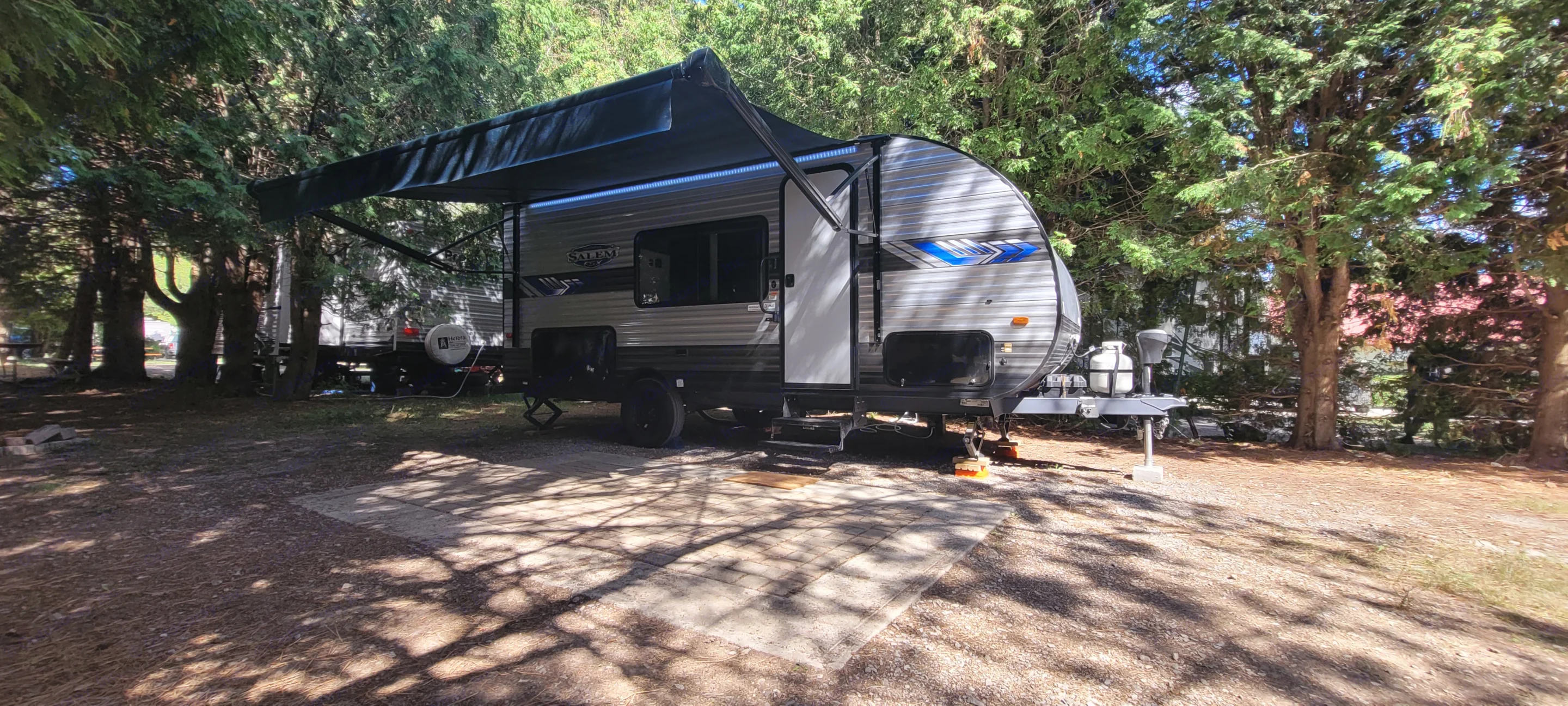 Experience outdoor living with this RV rental parked and leveled under its extended awning in a sunny, treed campsite. Forest River Salem FSX 2022