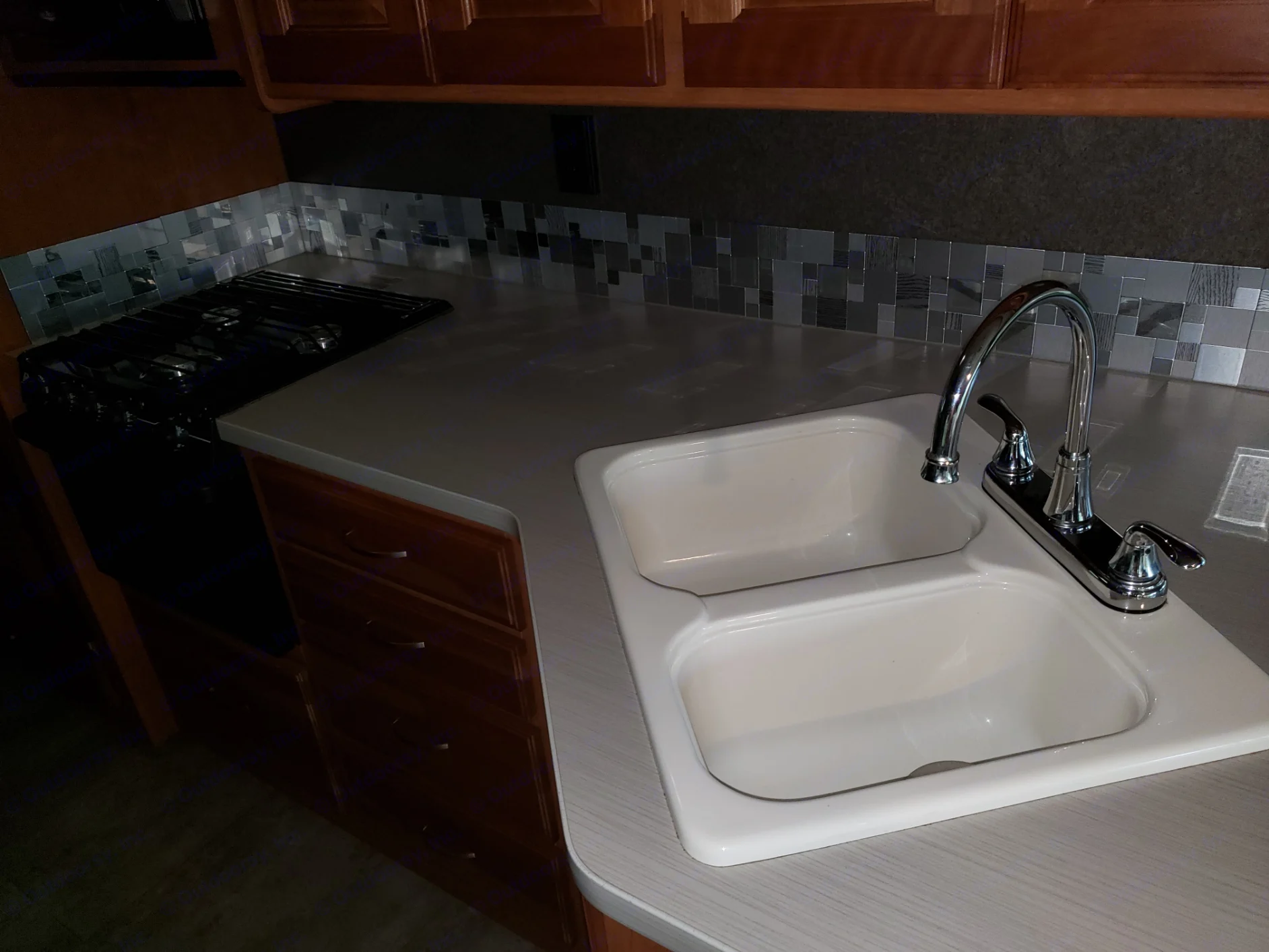 This modern RV rental kitchen features a gas stove, double sink, and sleek grey countertops with a mosaic backsplash.. Winnebago Vista 2017