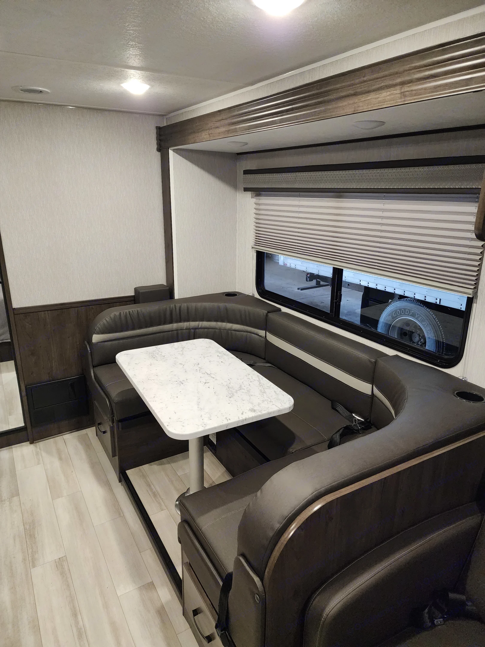 Bright RV rental interior features a versatile dinette with comfy seating, white table, and large window.. Coachmen Leprechaun 2023