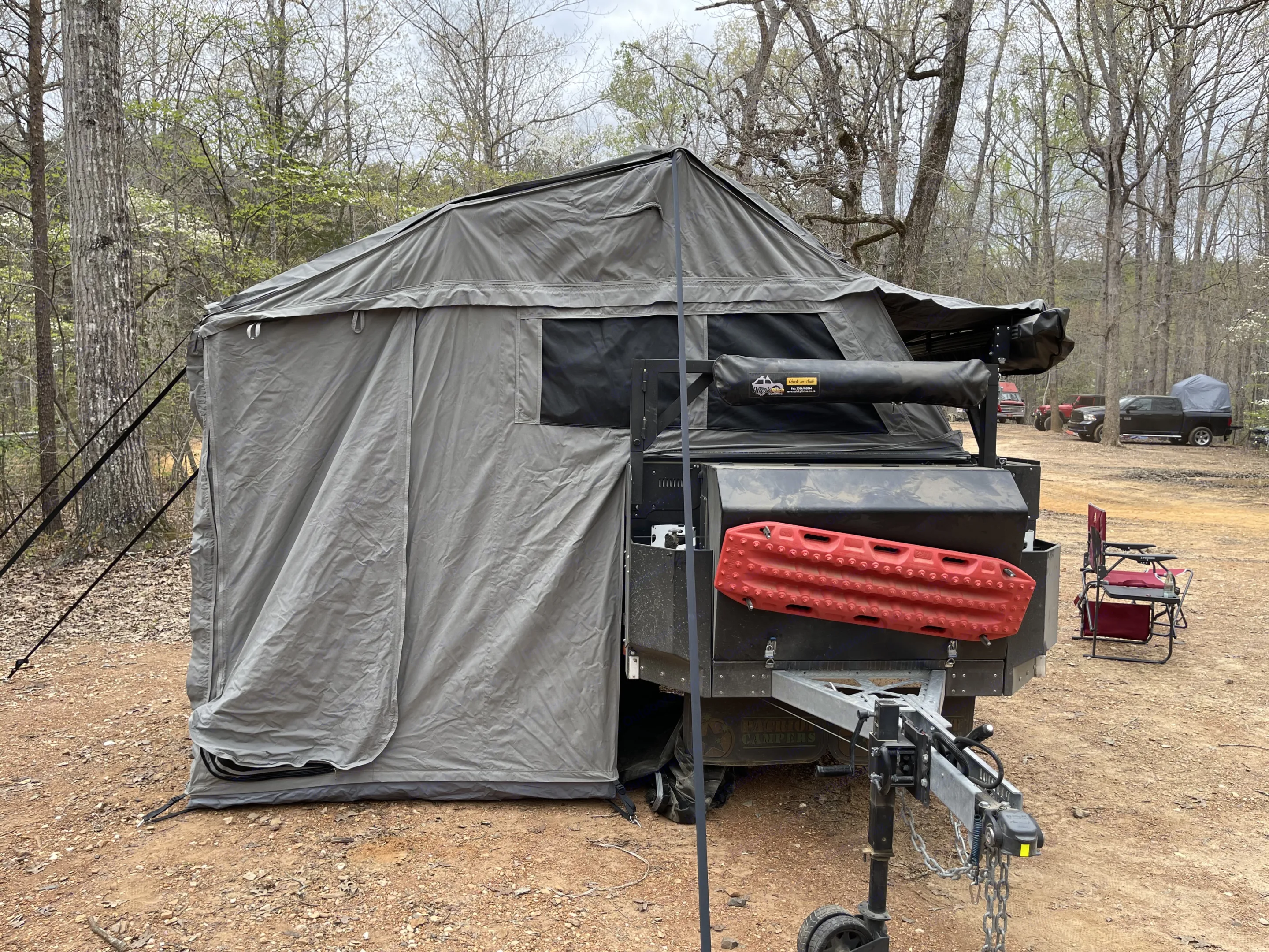 Front view of the trailer. This houses tent stakes, barbecue grill on a swing arm. Above the storage area is a swing arm with a shower tent on it. . Patriot X1 2021