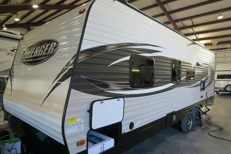 Avenger travel trailer, ready for RV rental, parked indoors showing its side profile.. Prime Time AVENGER 26BH 2017