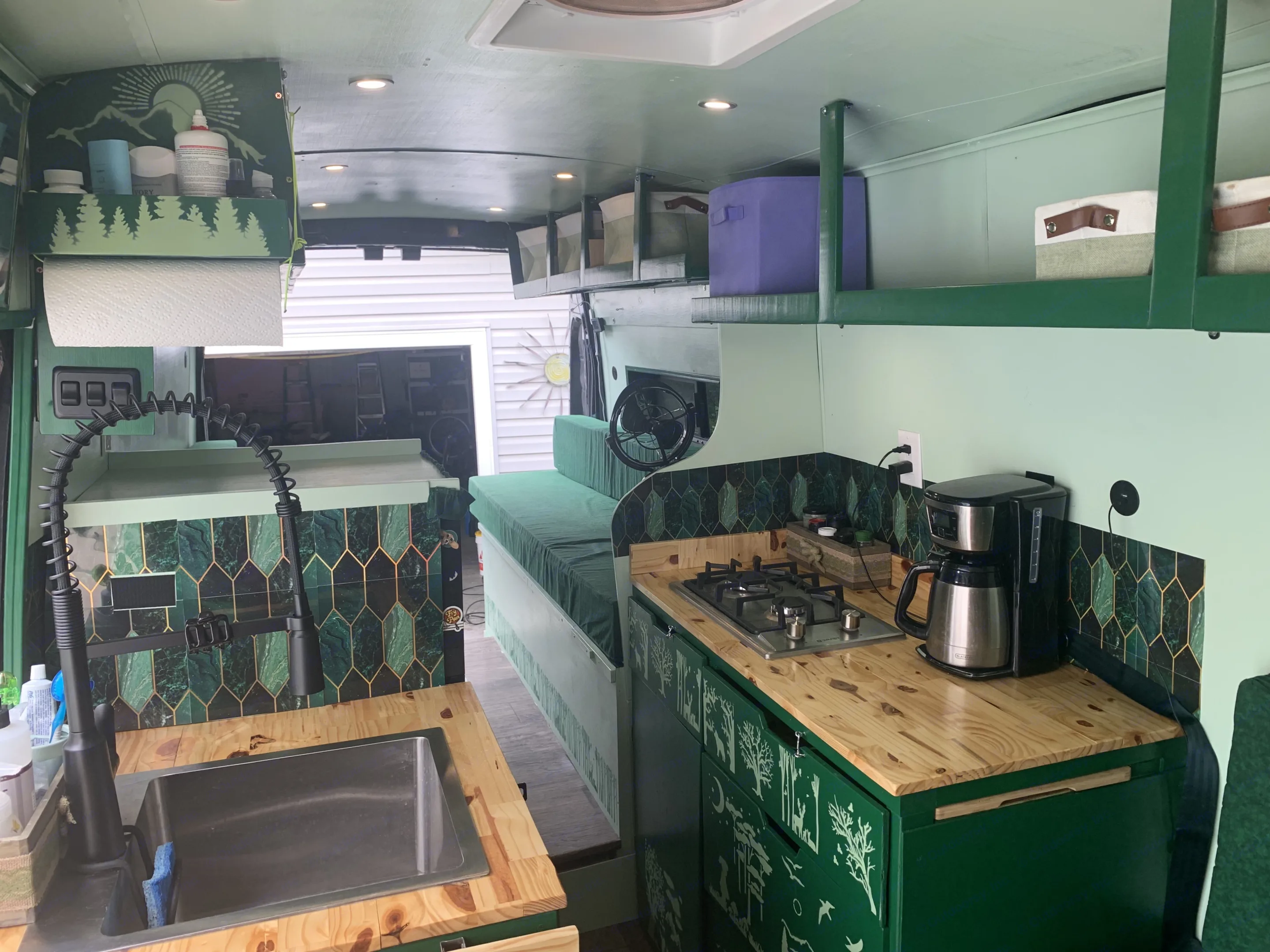 RV rental interior: vibrant green van features a detailed kitchen with patterned backsplash, wood counters, and stenciled nature cabinets.. Ford Transit 2022