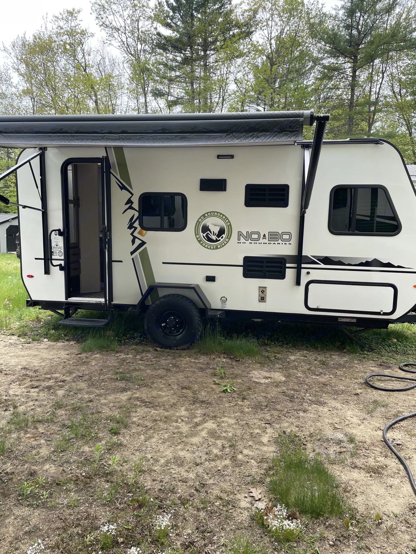 A white Forest River No Boundaries travel trailer RV rental with an extended awning, perfect for your outdoor adventures.. No Boundaries 16 2020