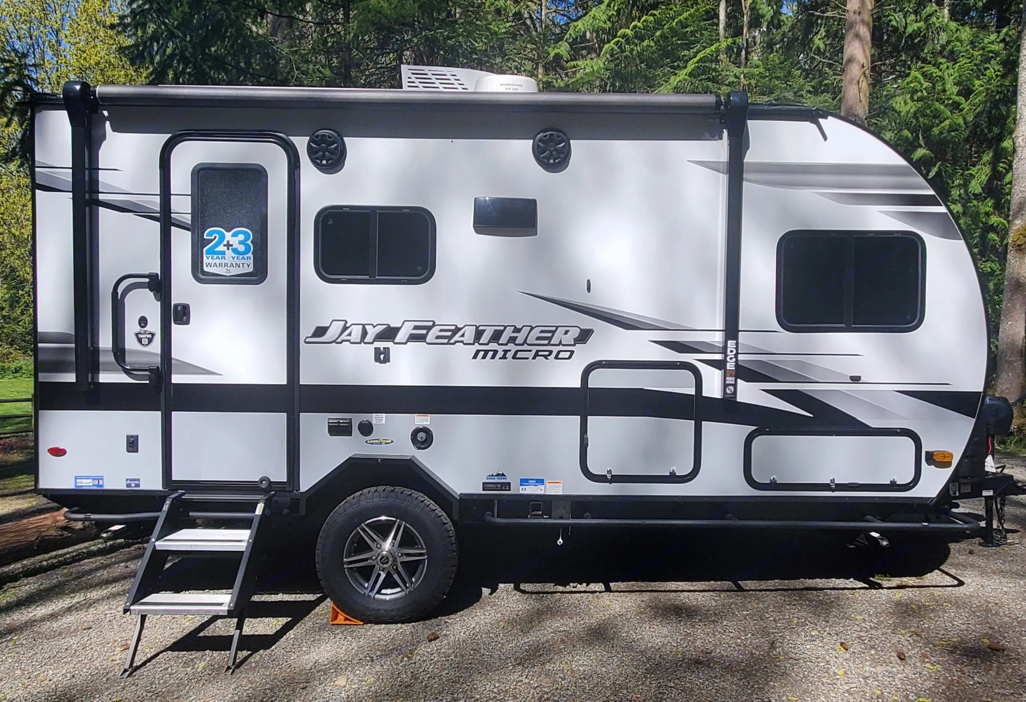 Side view of a Jay Feather Micro travel trailer, an excellent RV rental option. Shows graphics, door, steps, and roof antenna.. Jayco Jay Feather Micro 2022