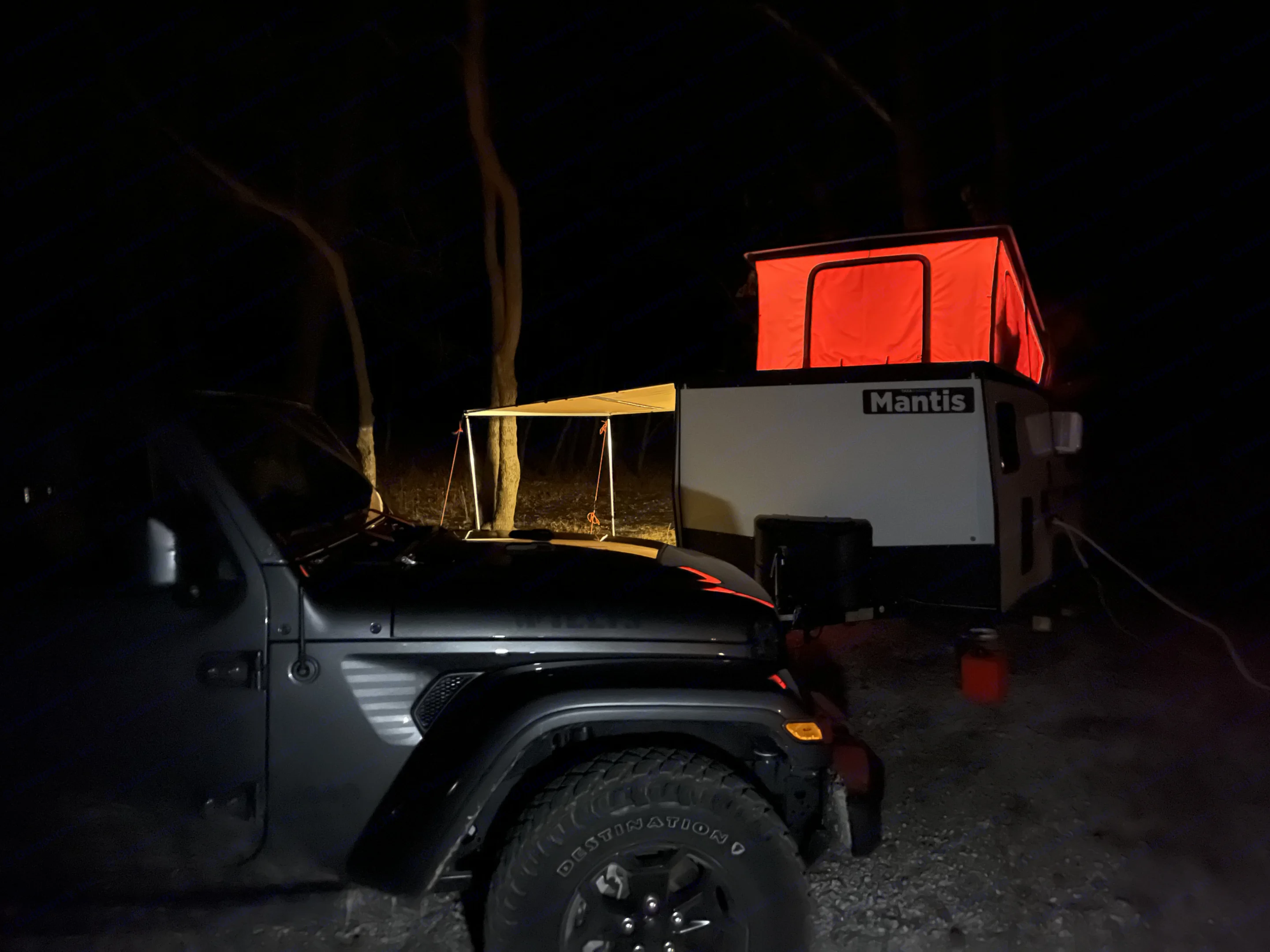 RV rental camping at night: Dark Jeep & illuminated Mantis camper with red pop-up tent & awning.. TAXA TAXA Trailer 2021