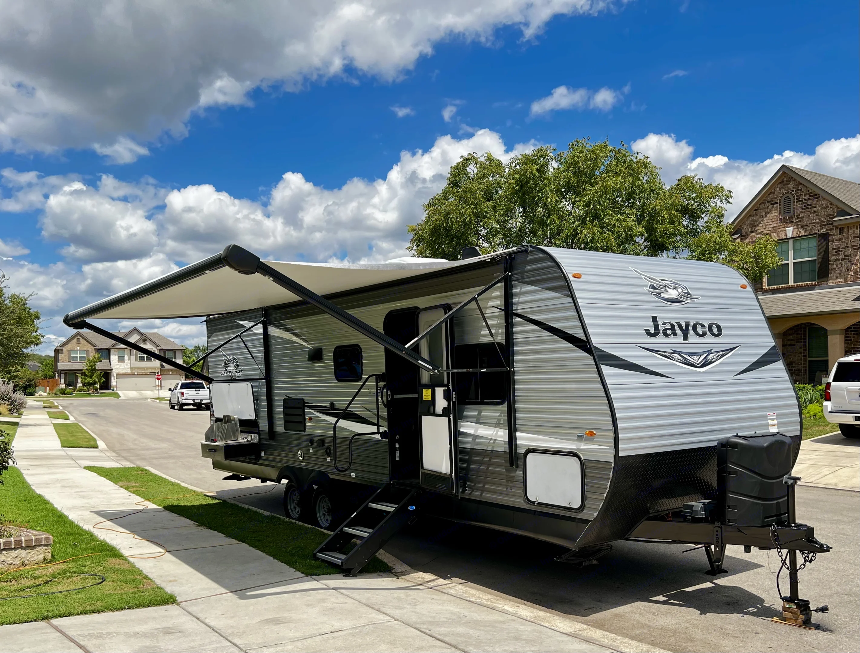 Jayco travel trailer RV rental, awning extended, parked on a street under a cloudy sky. Ready for adventure!. Jayco Jay Flight SLX 2020