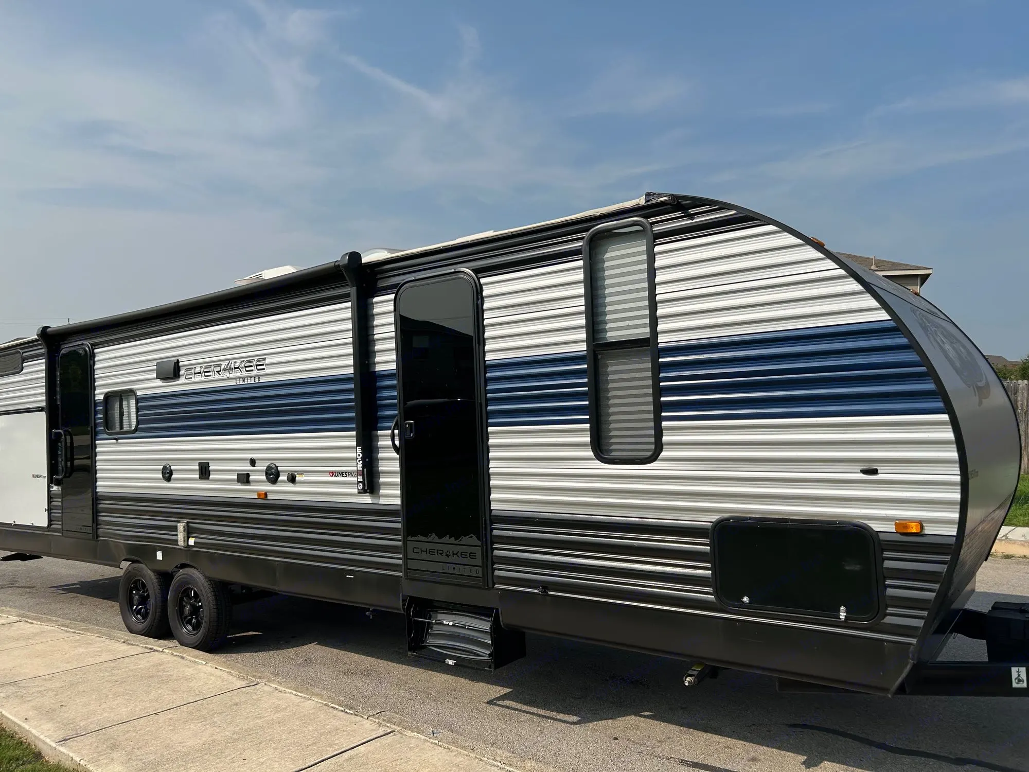This large Cherokee travel trailer, featuring distinctive blue, white, and black stripes, is perfect for an RV rental adventure.. Forest River Cherokee 2022
