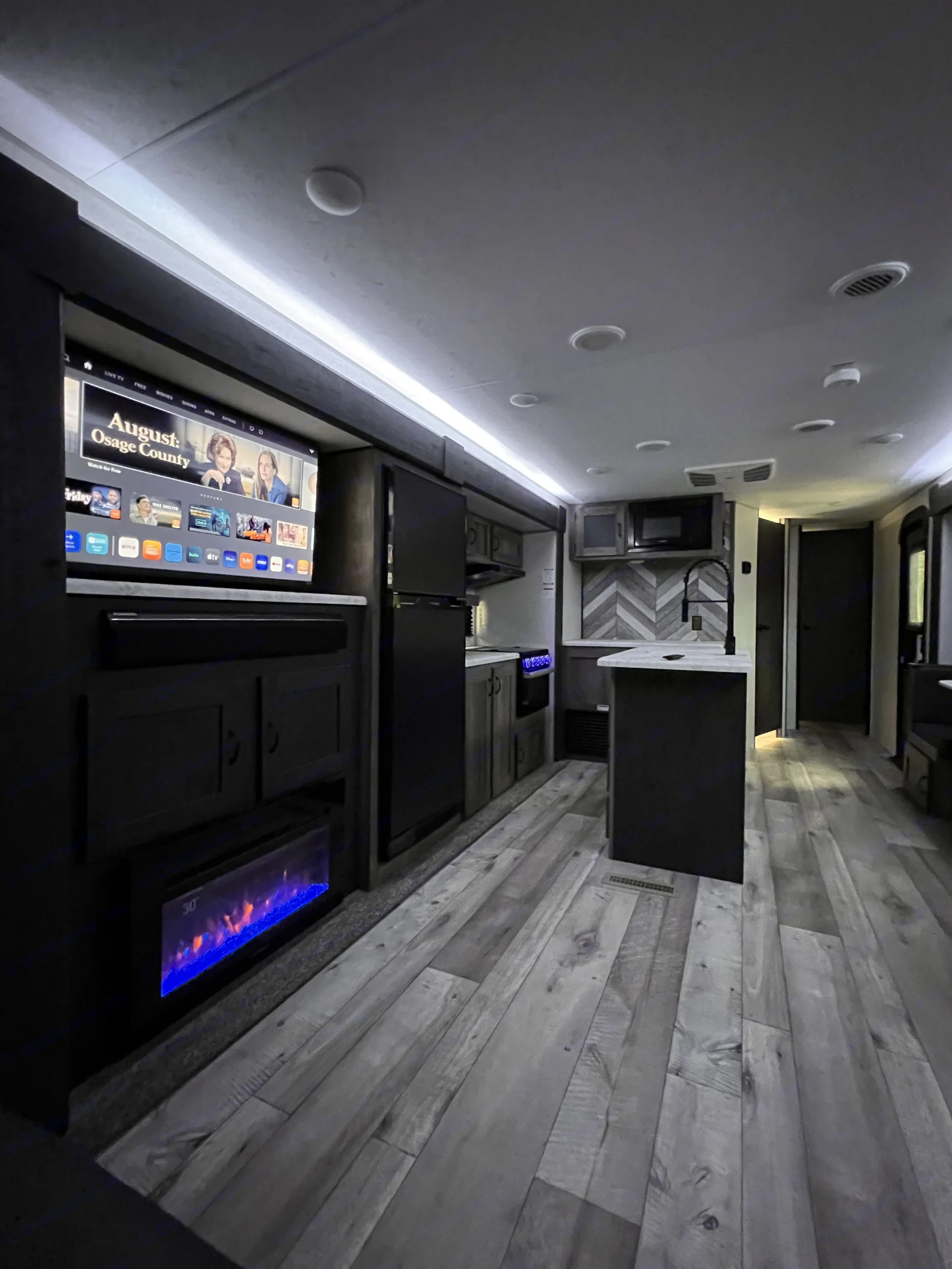 Spacious RV rental interior with modern kitchen, living area featuring a TV and electric fireplace, and wood-look flooring.. KZ Sportsmen LE 303KBLE 2021