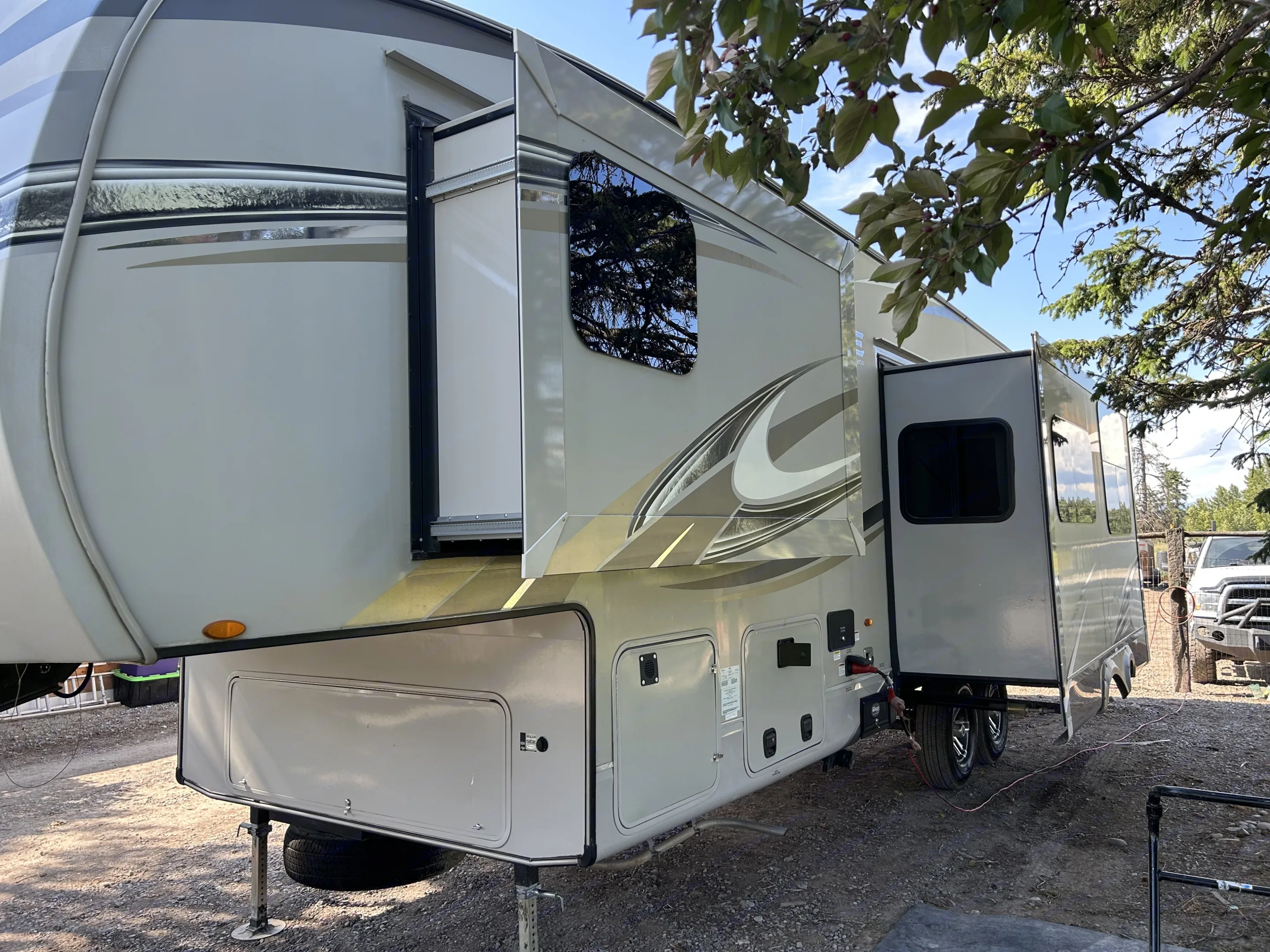 Modern fifth-wheel RV rental showcasing its expanded living space with slide-outs in a sunny campsite.. Jayco Eagle HT 2018