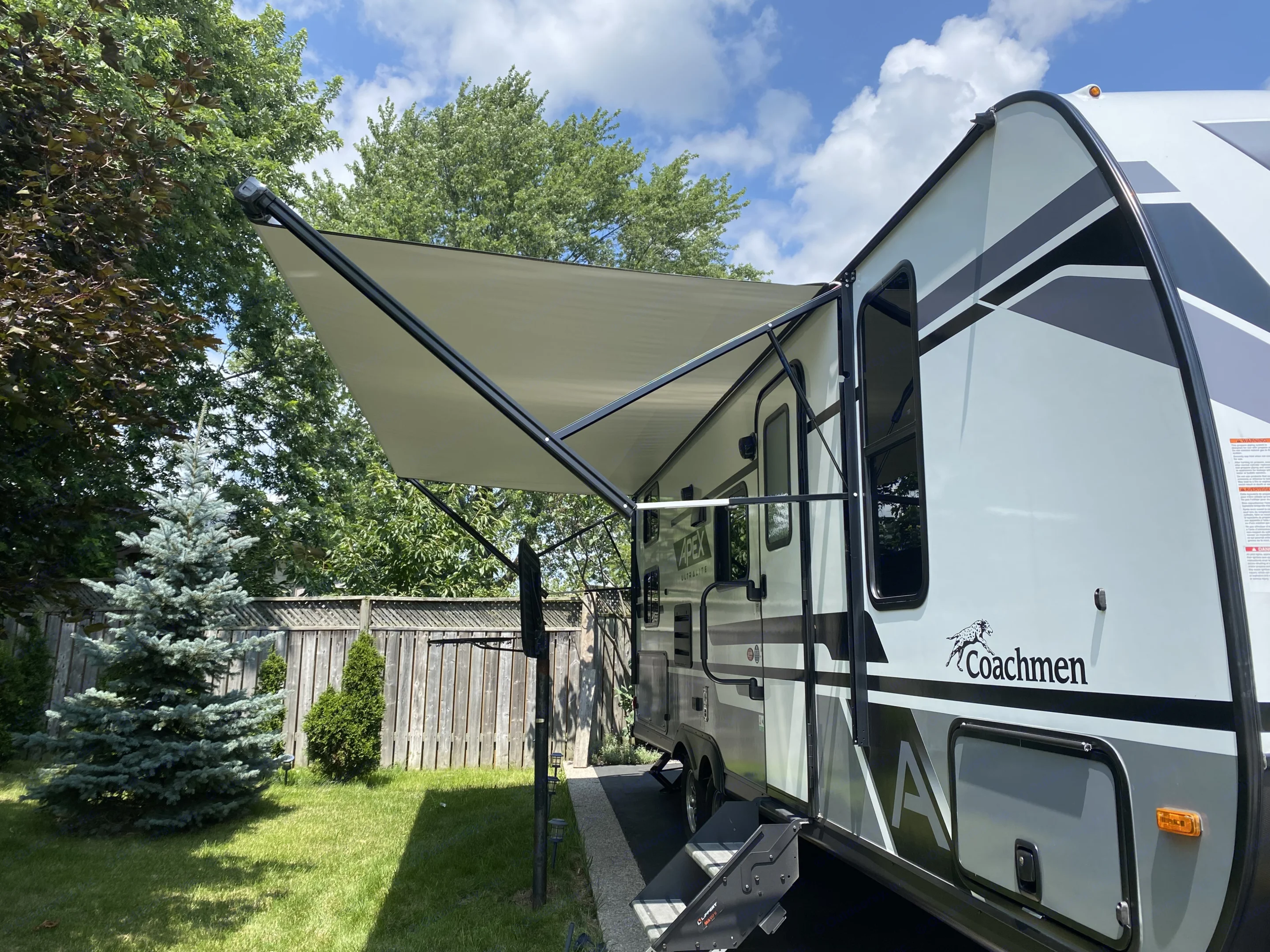 The entrance side of the trailer with the awning out.. Coachmen Apex 2023