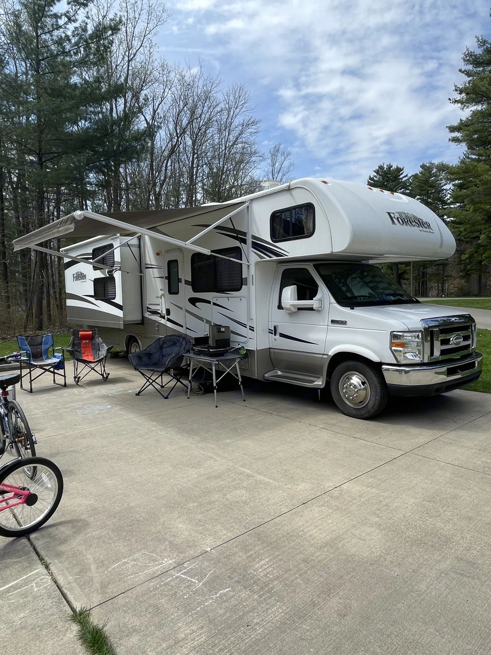 Spacious RV rental at a wooded campsite with awning and slide-out extended, surrounded. Forest River Forester 317DS 2014
