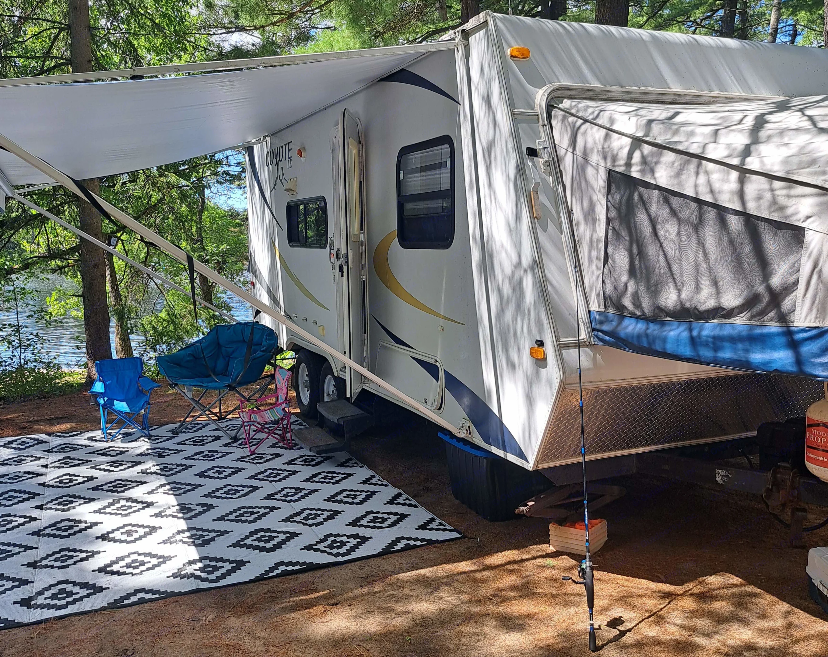 Enjoying a peaceful lakefront campsite with an RV rental, complete with an extended awning, chairs, and a fishing rod.. Other Other 2008