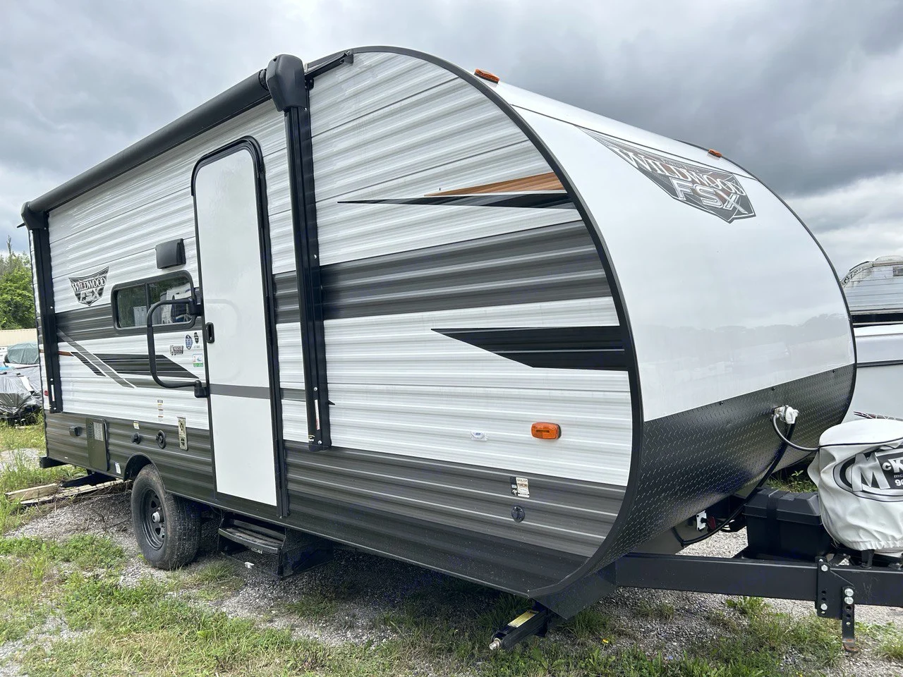 Wildwood FSX travel trailer RV for rent. This modern RV is white & grey, parked on gravel with grass.. Forest River Wildwood 2022