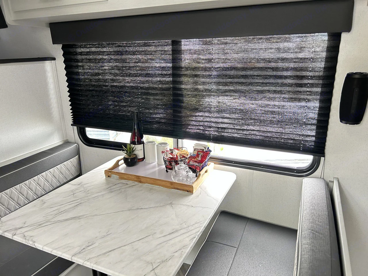 An RV rental's dinette area features a marble table, cozy bench seats, and a window with black blinds. Ready for travel.. Forest River Wildwood 2022
